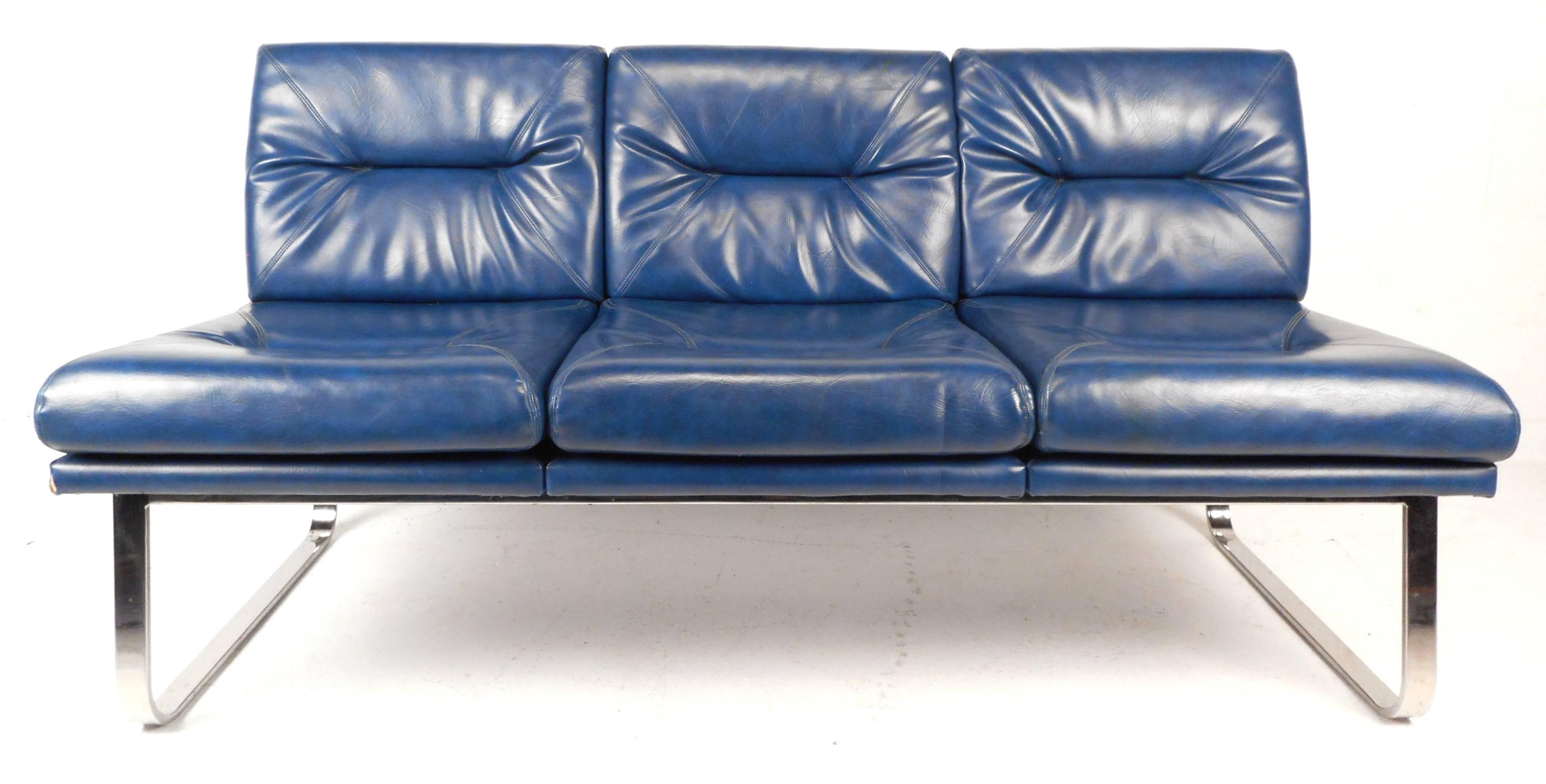 This stunning Mid-Century Modern sofa features unique chrome base and beautiful royal blue vinyl upholstery. The stylish design makes it perfect for any setting. Please confirm item location (NY or NJ).