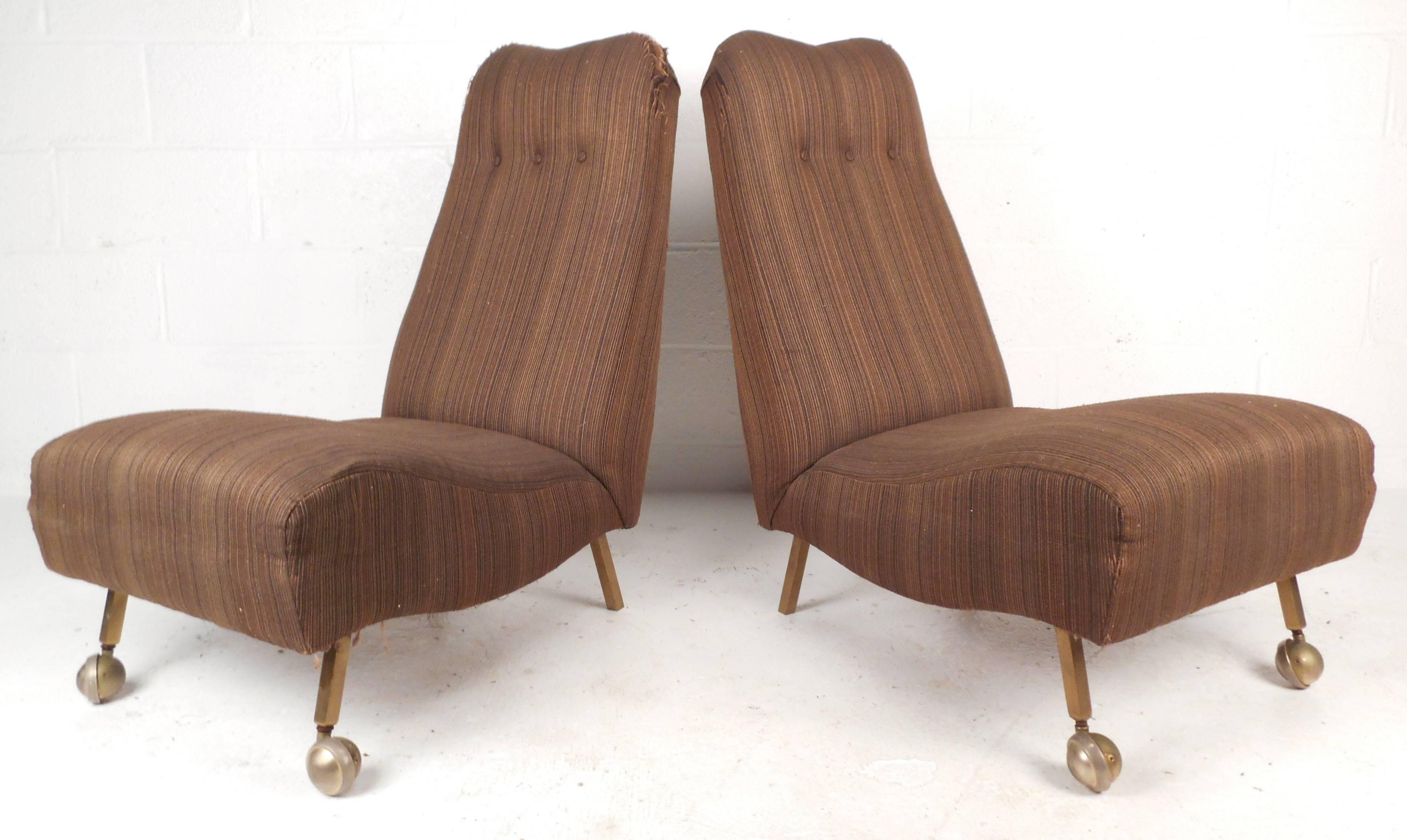 Gorgeous pair of Mid-Century Modern slipper chairs with tufted high backrests, thick comfortable seats, and brass feet offer stylish seating with an emphasis on comfort. The unique style features a sculpted brass handle on the backrest and sturdy