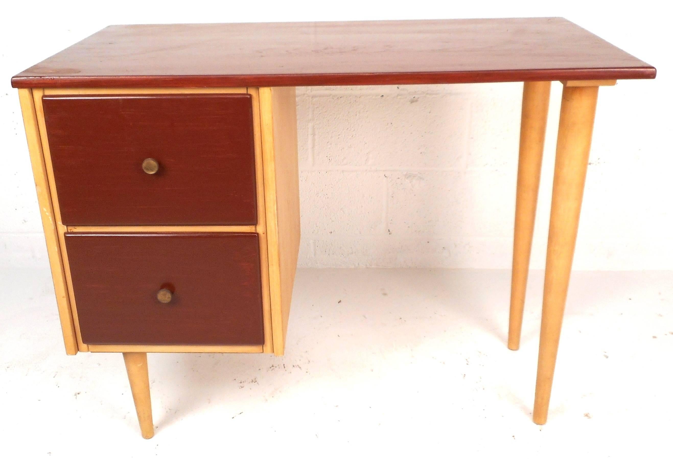 Lovely Mid-Century two tone desk features maple and walnut wood in a petite design. The stylish brass pulls and tapered legs make it perfect for any interior. Please confirm item location (NY or NJ).