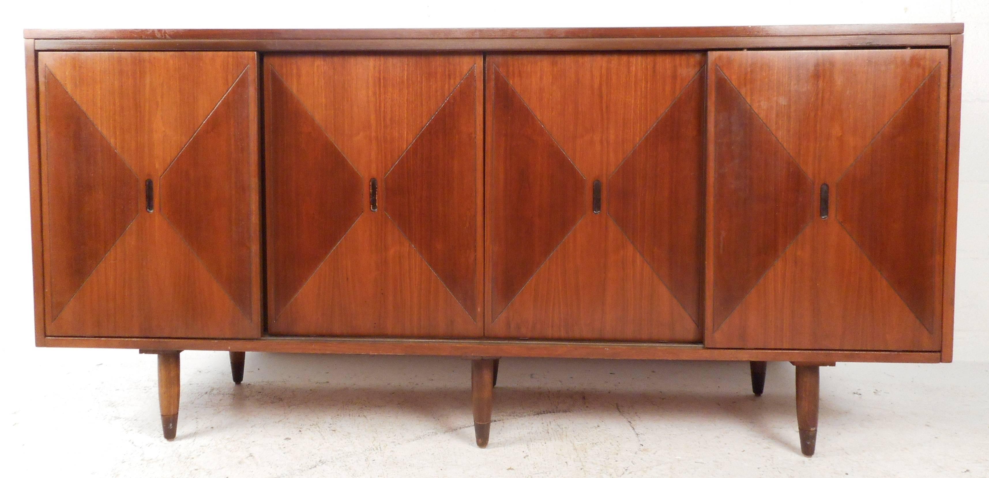 Stunning modern walnut credenza or server features graphical rosewood inlays on the sliding door fronts. Stylish brass capped feet and abundance of storage space make it perfect for any setting. Please confirm item location (NY or NJ).