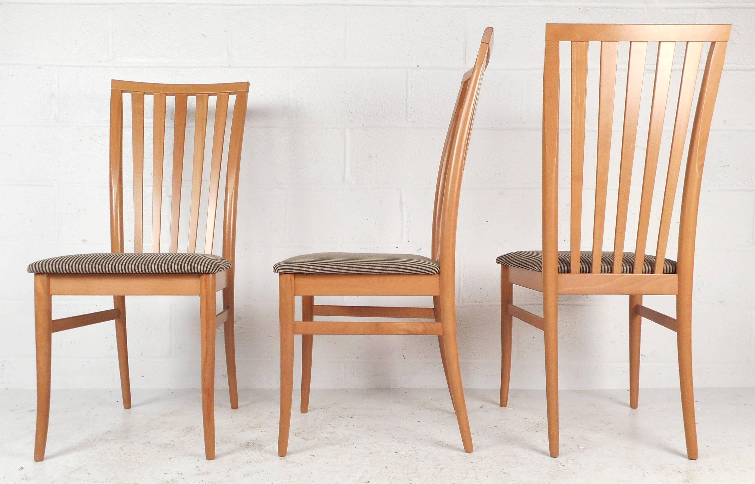 This beautiful set of four Mid-Century style modern dining chairs features unique curved legs, upholstered seating, vintage maple finish, and ergonomic vertical slat back rests. Please confirm item location (NY or NJ).