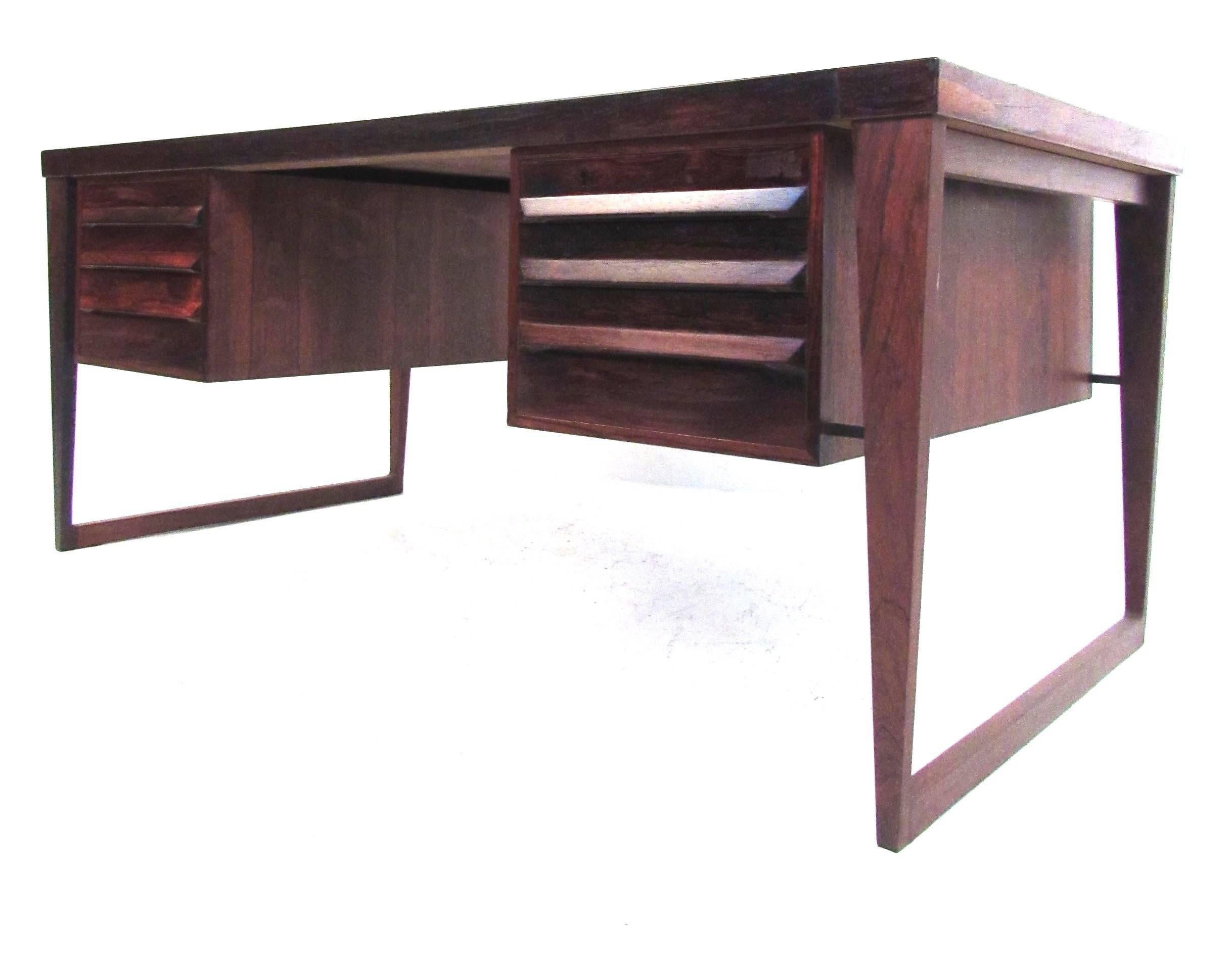 This stunning vintage rosewood desk features the masterful Mid-Century design of Kai Kristiansen. Unique sculpted drawer pulls, tapered floating sled legs, and dovetailed joints showcase the impeccable attention to detail taken in the construction