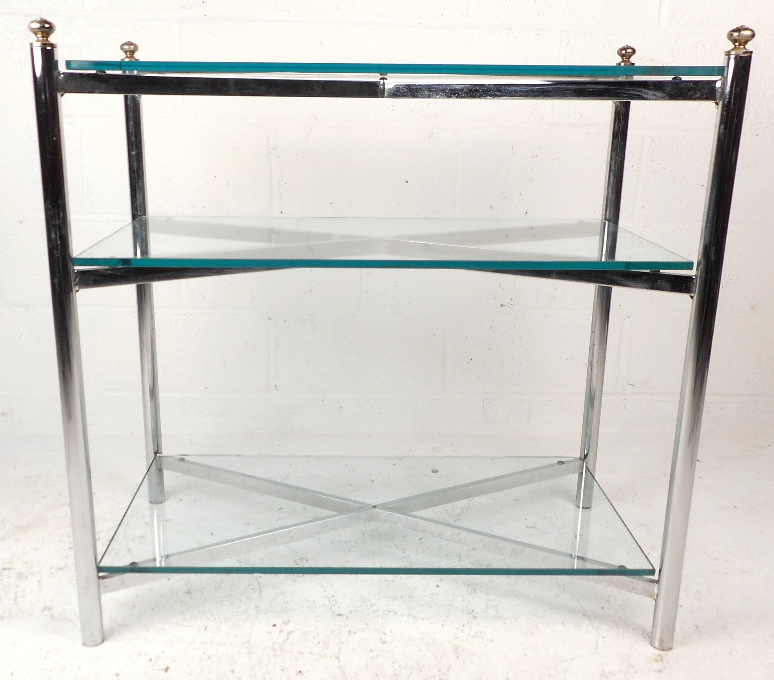 Unique modern chrome and glass display shelf features three glass shelves, chrome supports, and brass trim in the style of Maison Jansen. Unique design fits a variety of uses from storage to display, all while adding style and grace to any interior.