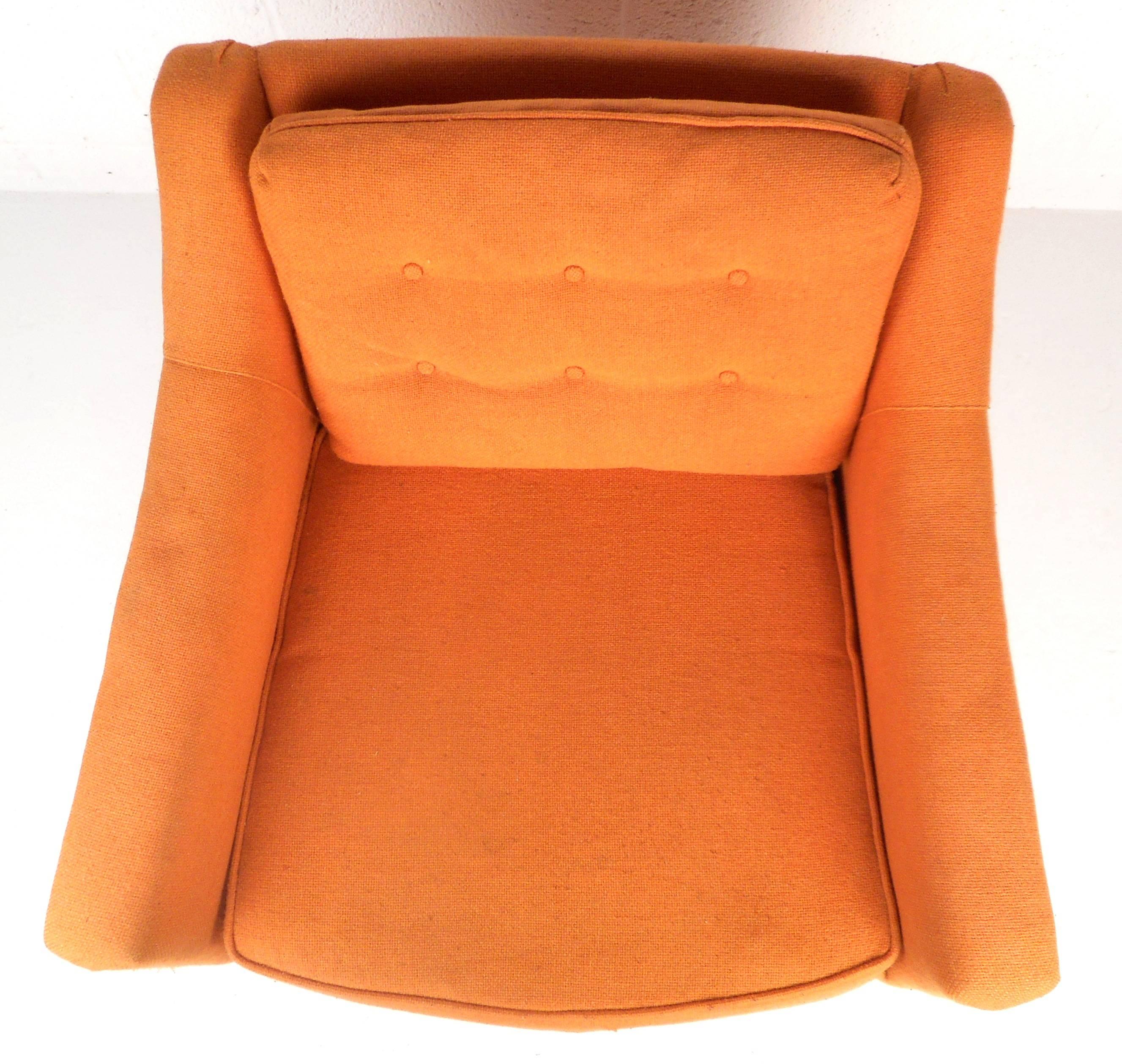 This elegant Mid-Century lounge chair by Selig features sculpted sloping armrests, tapered walnut legs, and a tufted backrest. The stylish orange upholstery adds to the vintage appeal of the comfortable chair. Please confirm item location (NY or NJ).
