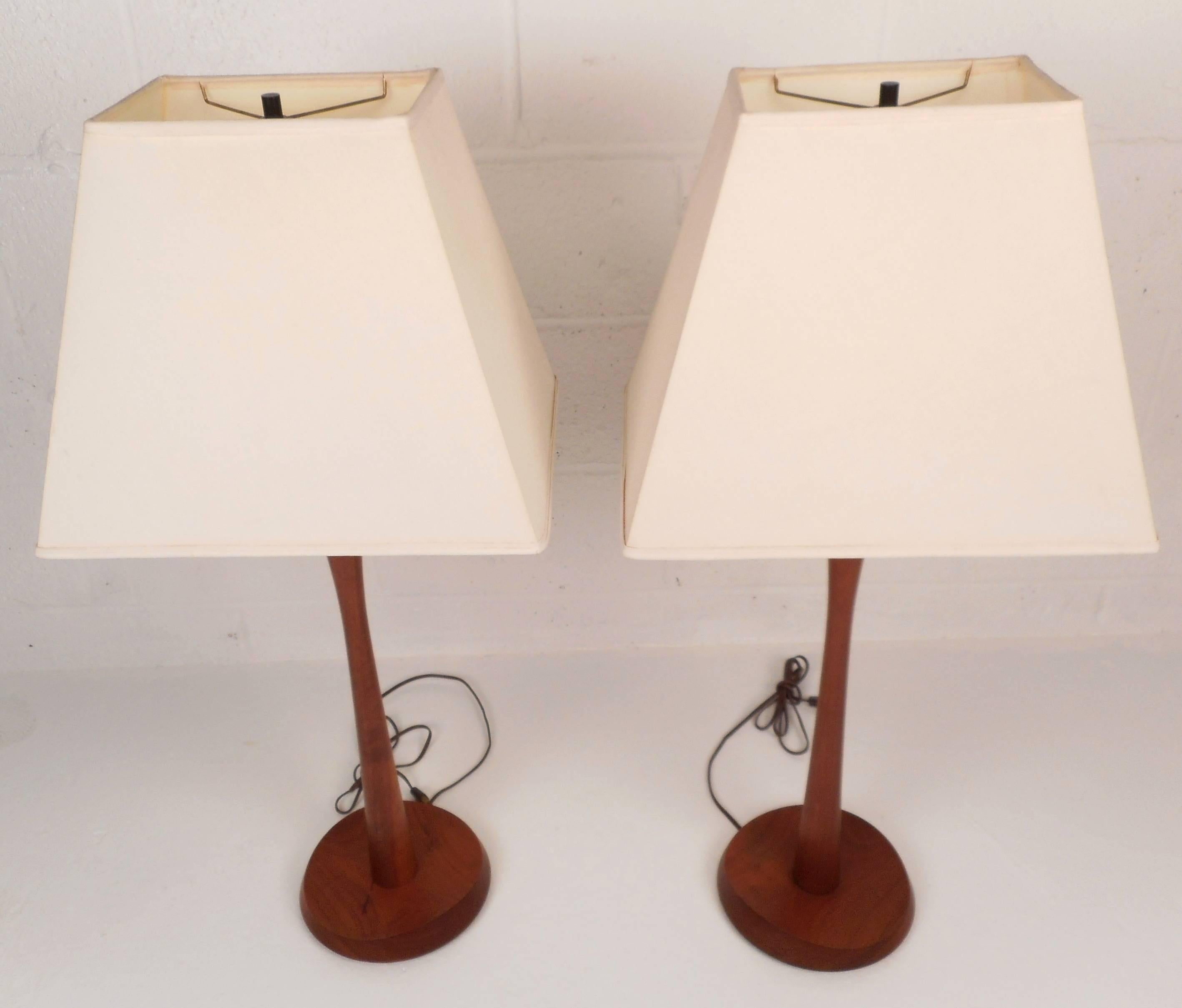 Elegant pair of vintage modern lamps feature unique sculpted bases complimented by bright white shades. They are made of solid teak and are sure to add mid-century style to any interior. Please confirm item location (NY or NJ).