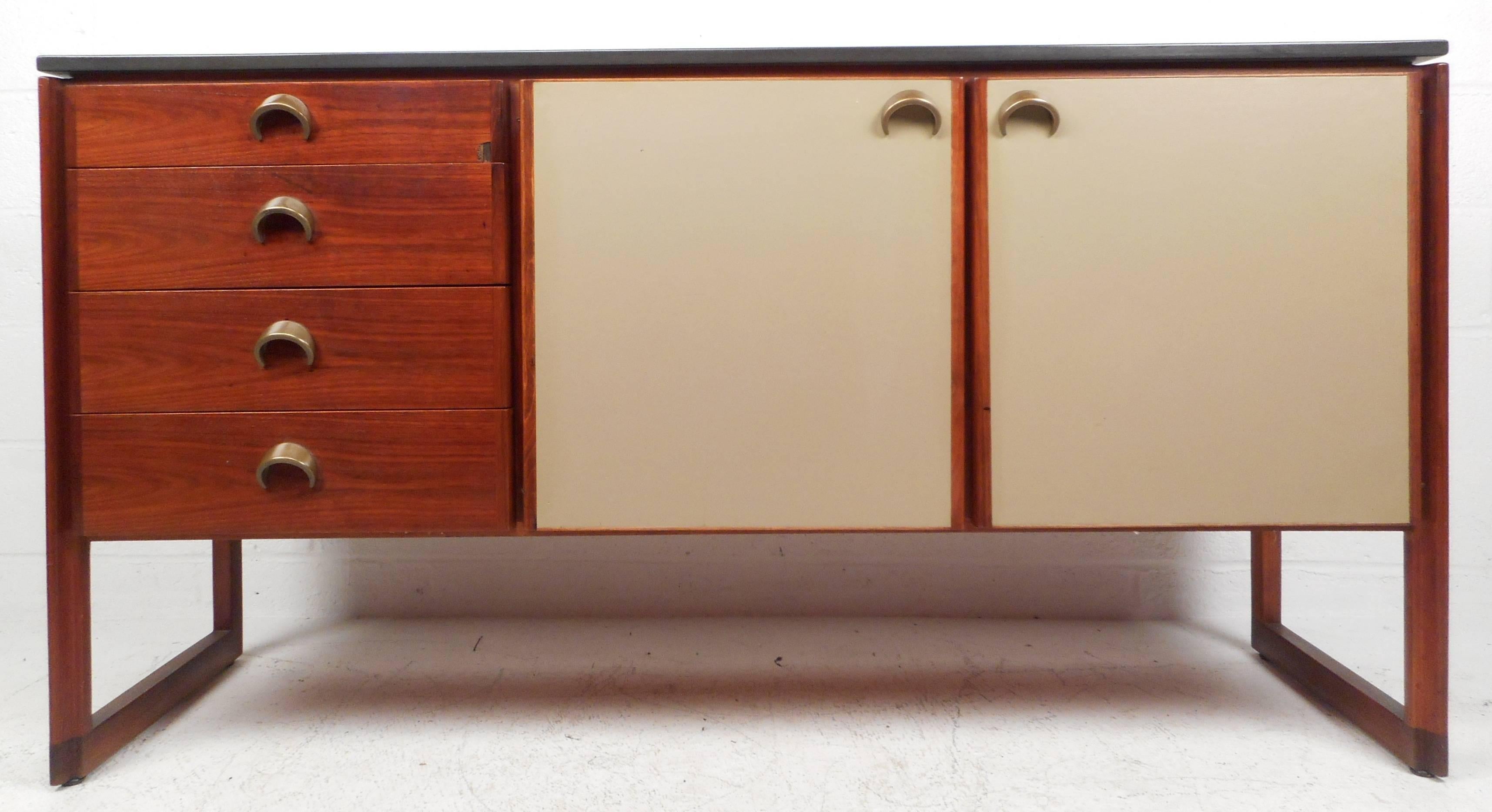 This divine vintage modern sideboard features a sleek black marble top, unique brass eclipse pulls, and off white leather cabinet fronts. The four drawers and two cabinets with shelving provide plenty of storage space while remaining true to the