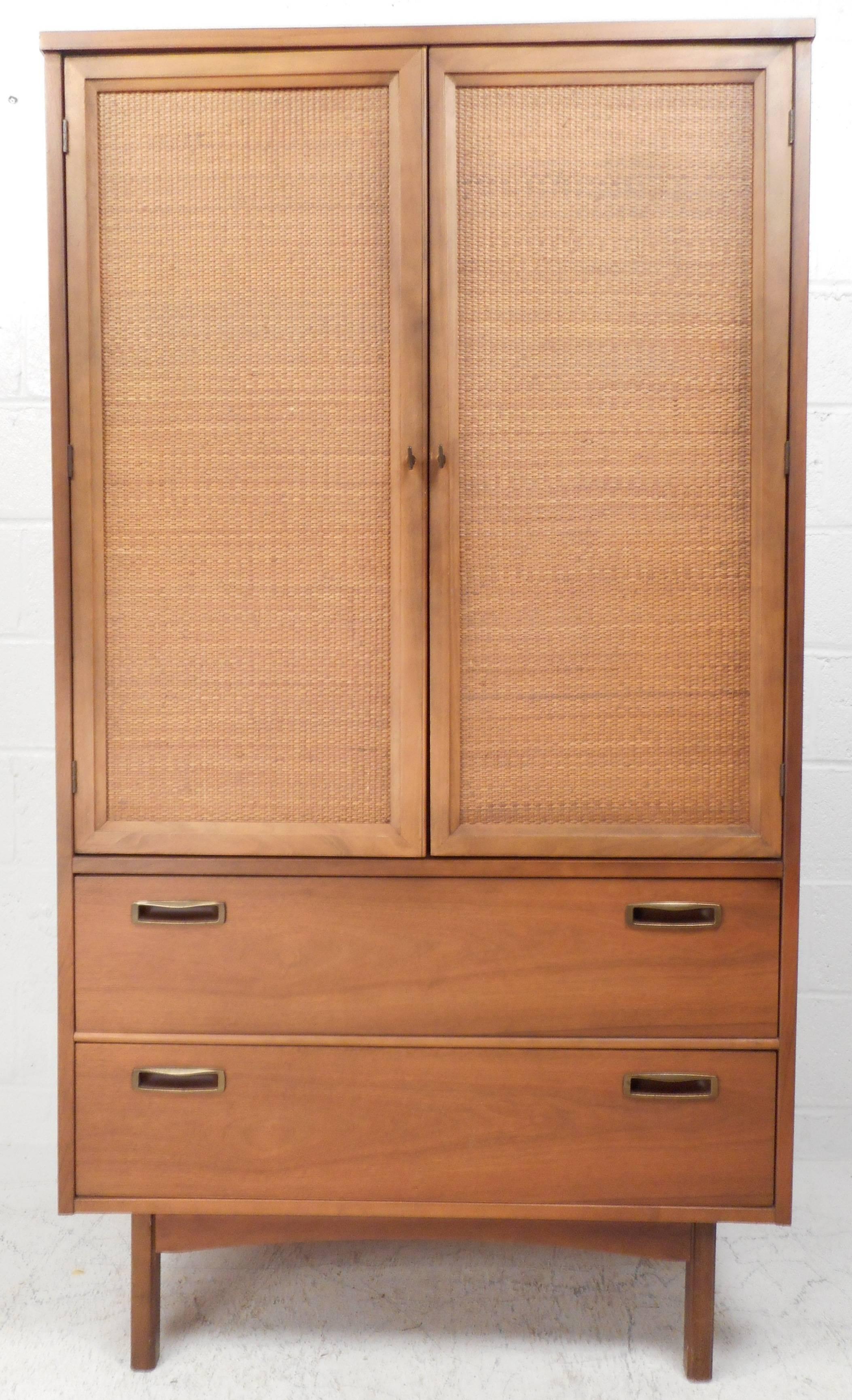 Impressive vintage modern wardrobe with stylish cane front cabinets, sculpted brass pulls, and vintage walnut finish. Two large drawers, three small drawers, and four shelves offer ample storage in any modern interior. Please confirm item location