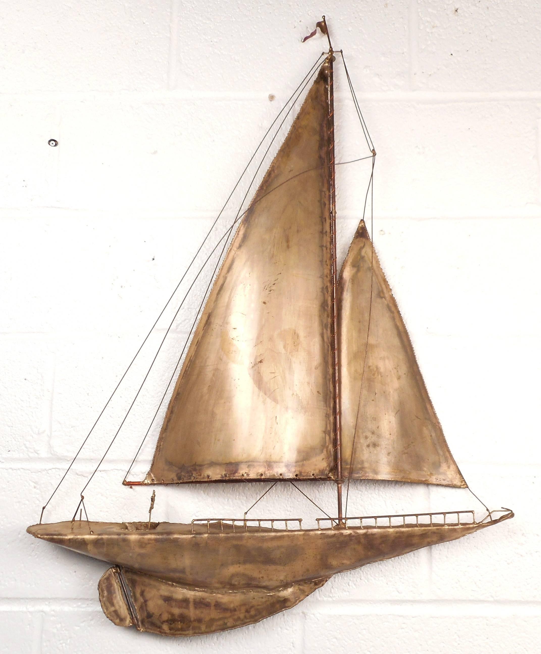 Stunning Mid-Century Modern metal sailboat wall art features intricate detailing from the mast to the keel. The unique design displays a miniature steering wheel, railing, rudder, and flag all patiently crafted by the designer. Perfect addition to