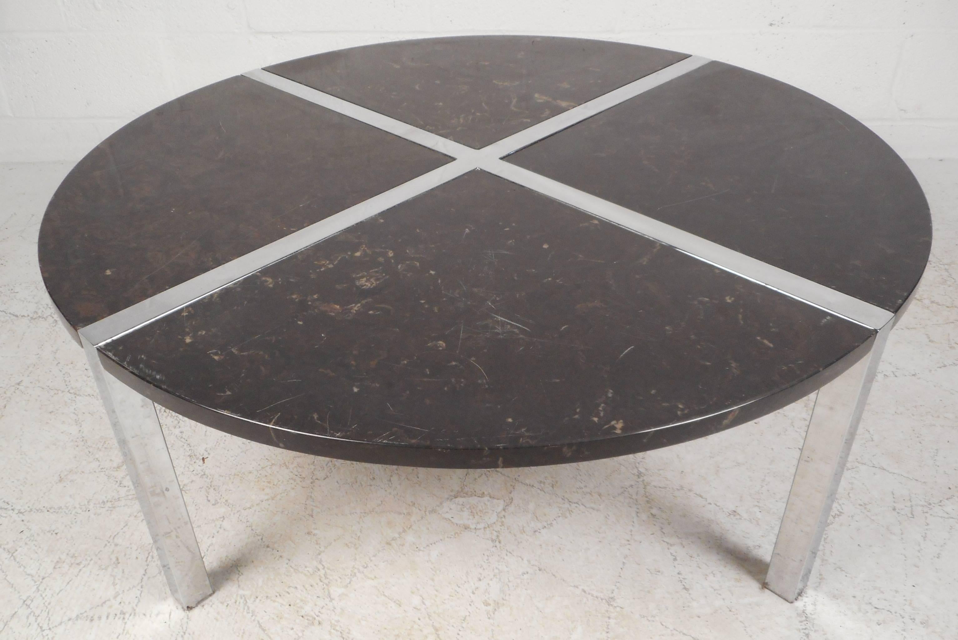 Impressive vintage modern round coffee table features four individual marble inserts and a thick chrome base. The sleek design allows easy movement and storage. Beautiful black marble top with strips of chrome forming an "X" shape make