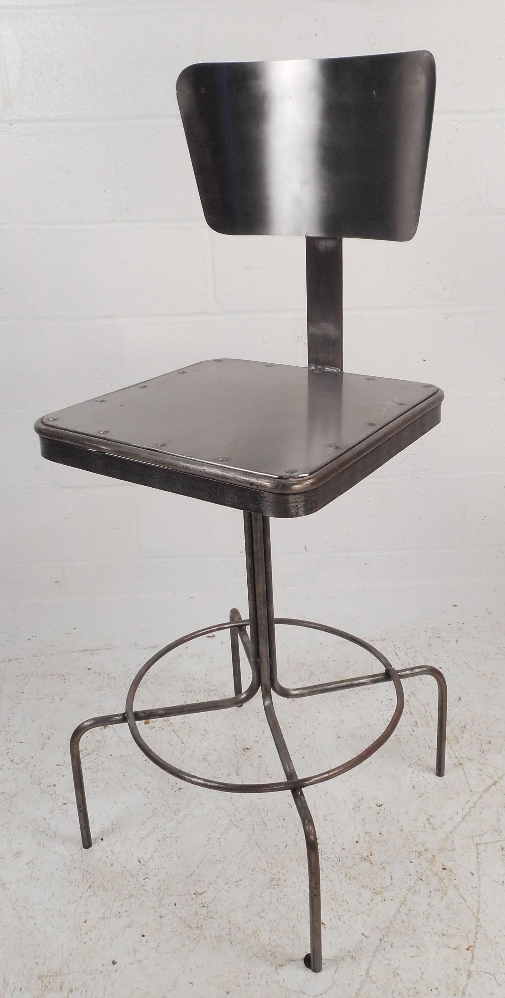  Industrial metal bar stool features unique curved backrest to provide extra comfort. The sleek four legged base is joined with a circular kick rest. The seat has rounded edges and rivets showcasing impressive industrial style design. Comfortable