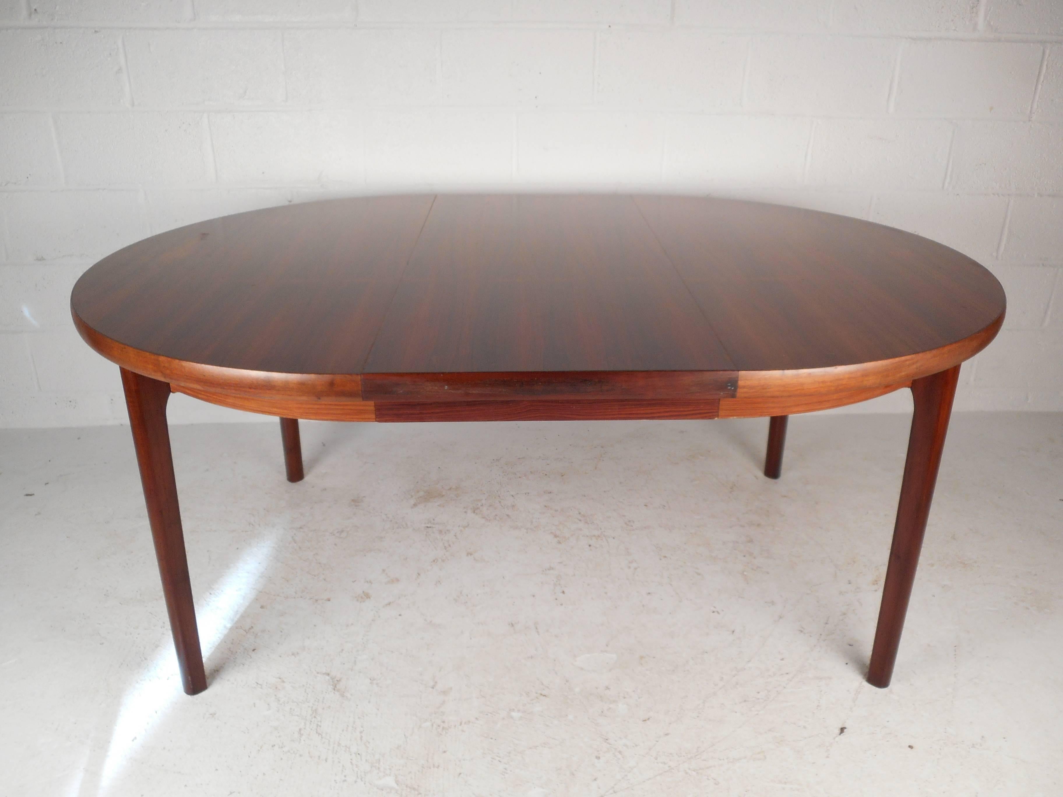 Gorgeous vintage modern rosewood dining table features unique rounded edges and one leaf to extend to 68