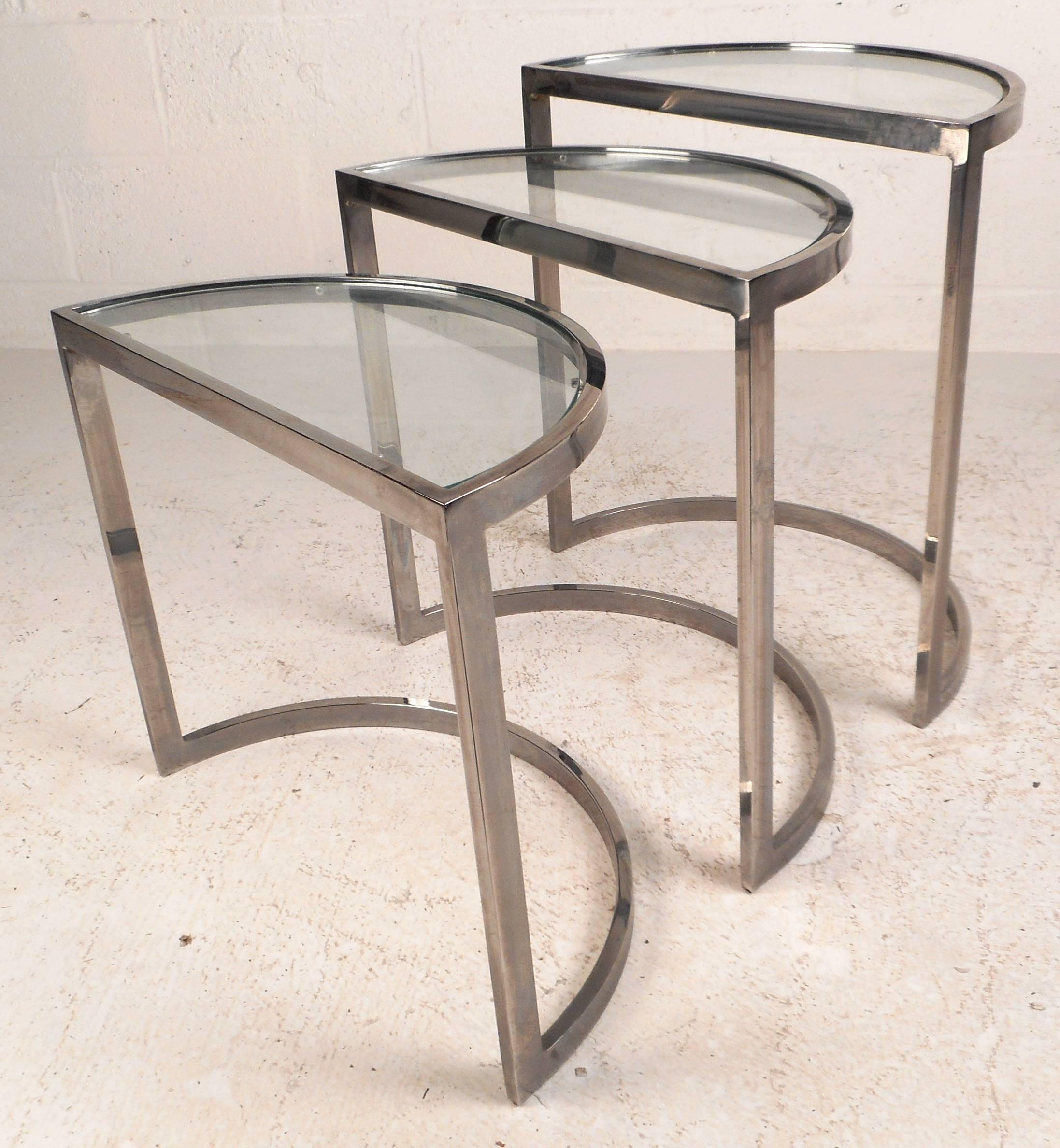 Stunning set of three vintage modern nesting tables feature a unique half-moon shape, a solid chrome frame, and a glass top. Versatile design allows the tables to fit comfortably inside each other for convenience. Easy storage and sleek design make