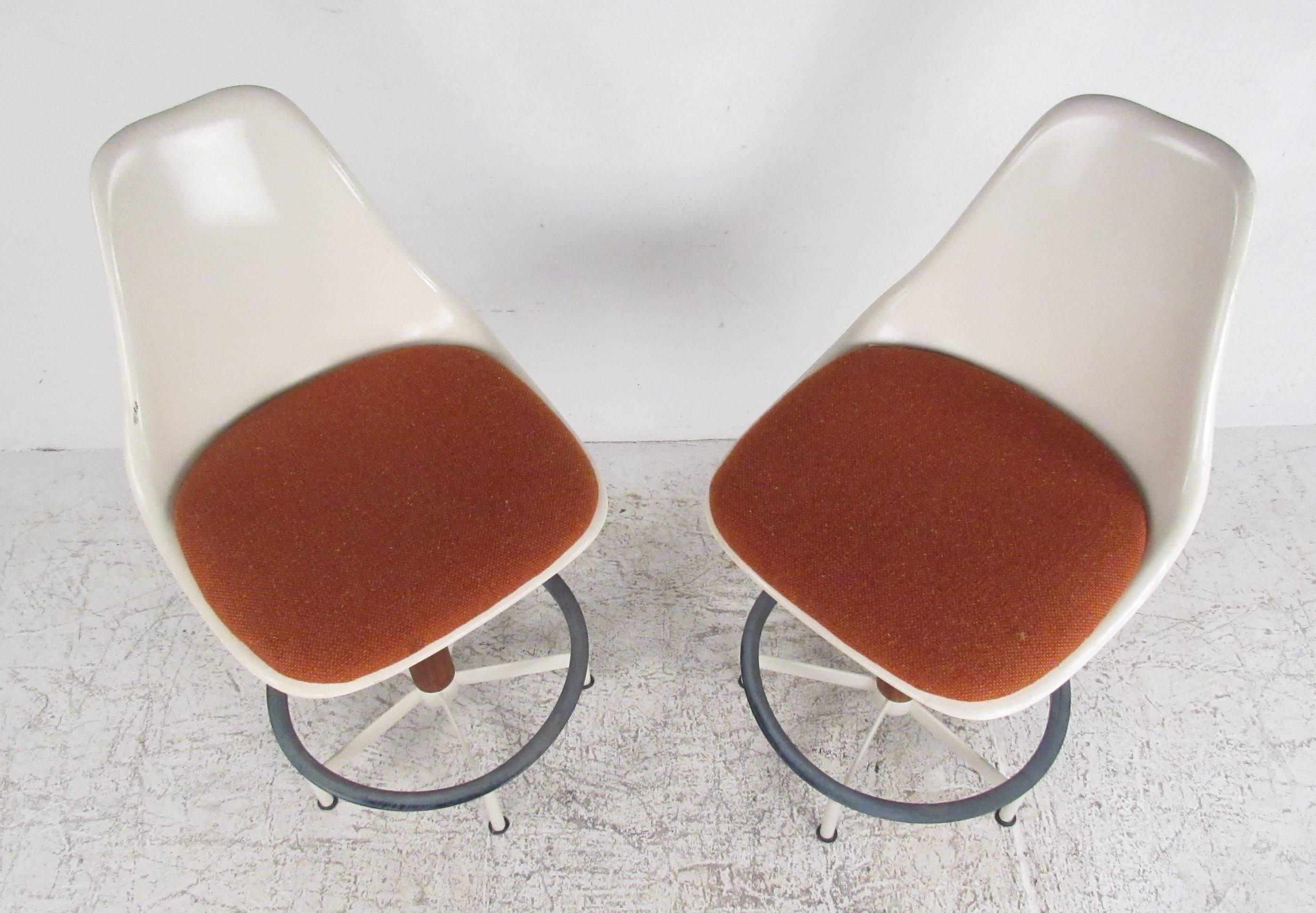 Pair of Mid-Century fiberglass shell stools with upholstered seats and a cast steel base manufactured by Burke Inc., Dallas, Texas. Please confirm item location (NY or NJ).
