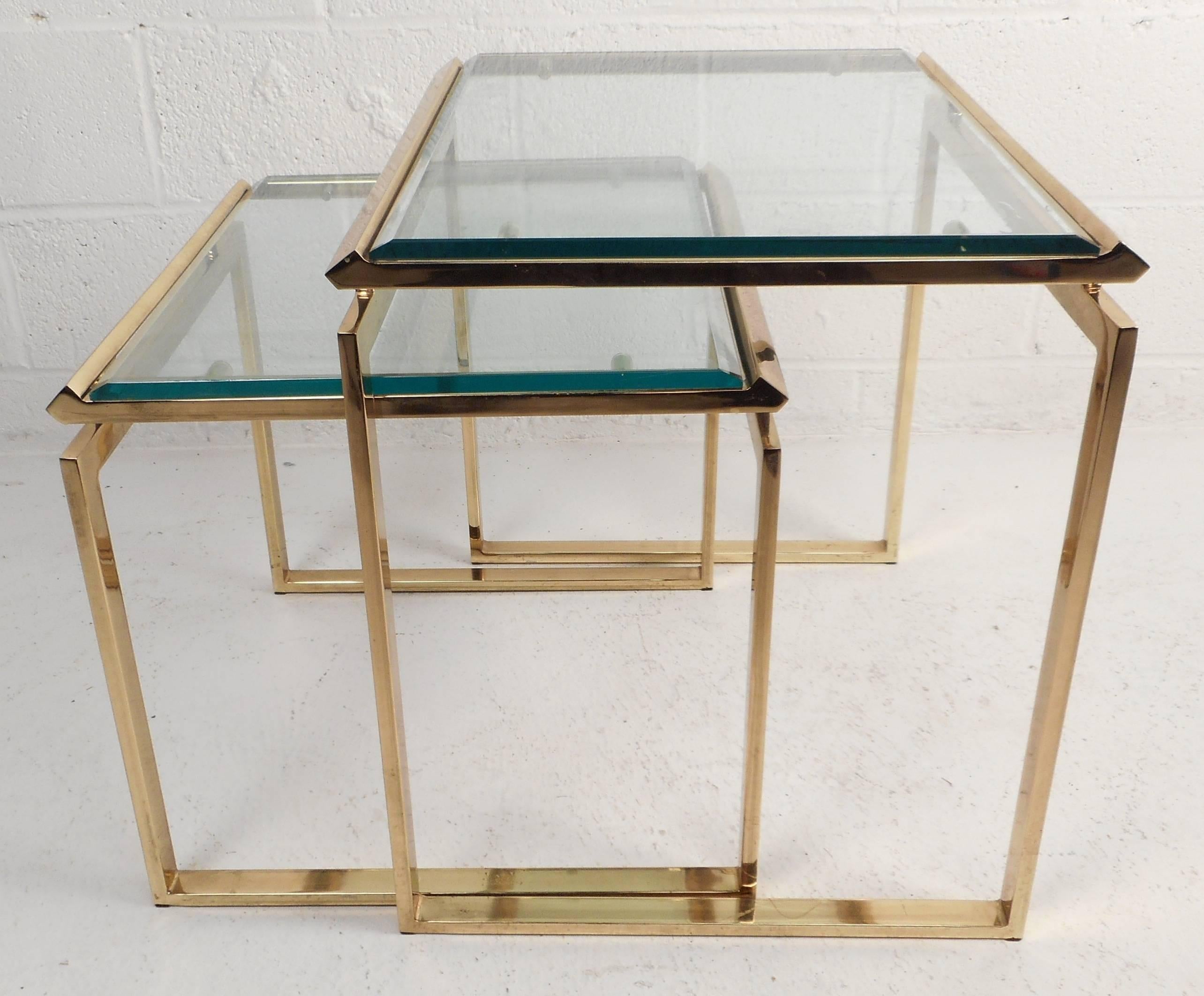 Gorgeous pair of vintage modern nesting tables feature unique beveled glass and brass edges. The thick green glass sits comfortably on top of the solid brass frame. The sleek design has a floating top and sled legs showing quality craftsmanship.