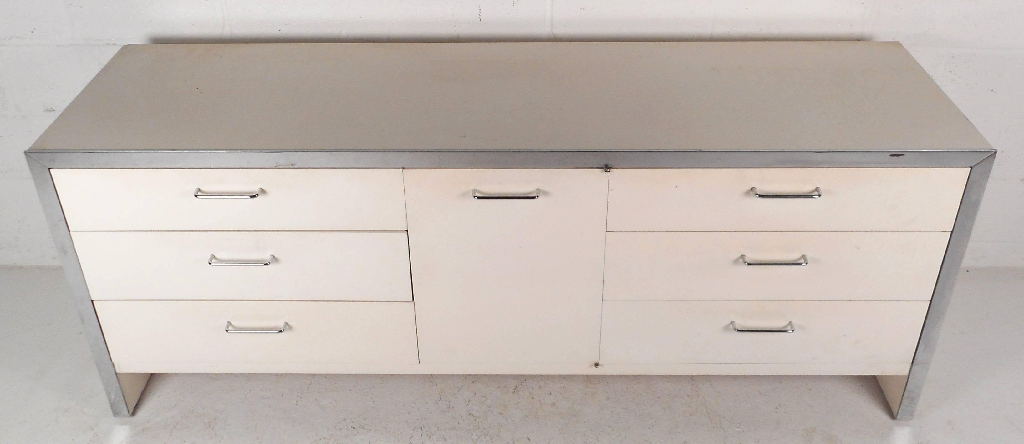 This beautiful vintage modern sideboard features ultra white Formica laminate and chrome trim. The sleek design offers plenty of room for storage within its six large drawers and three hidden small drawers. Unique chrome pulls and sturdy