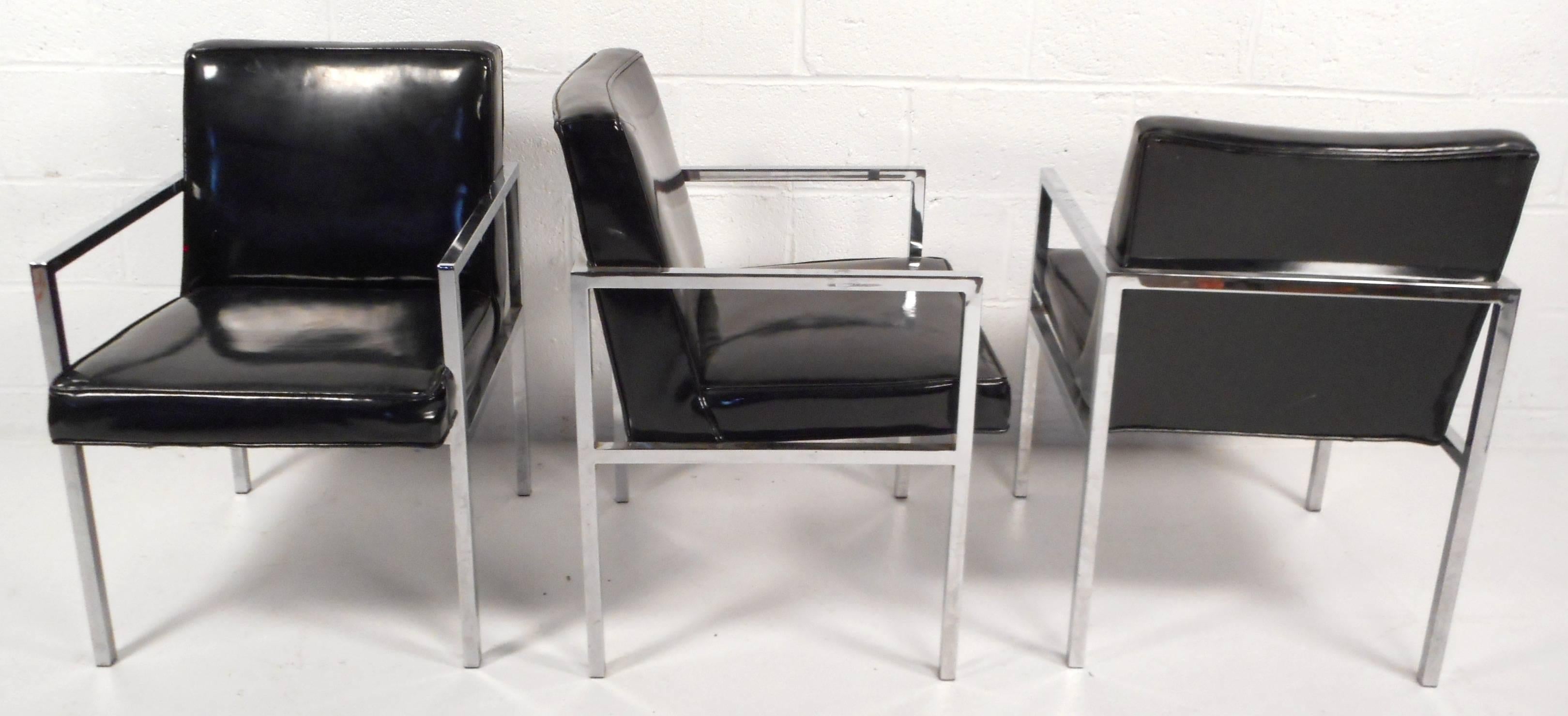 Beautiful set of four Mid-Century Modern dining chairs feature black vinyl and a heavy chrome frame. Sleek design with thick cushions and wide seating ensures comfort and style in any modern interior. Please confirm item location (NY or NJ).