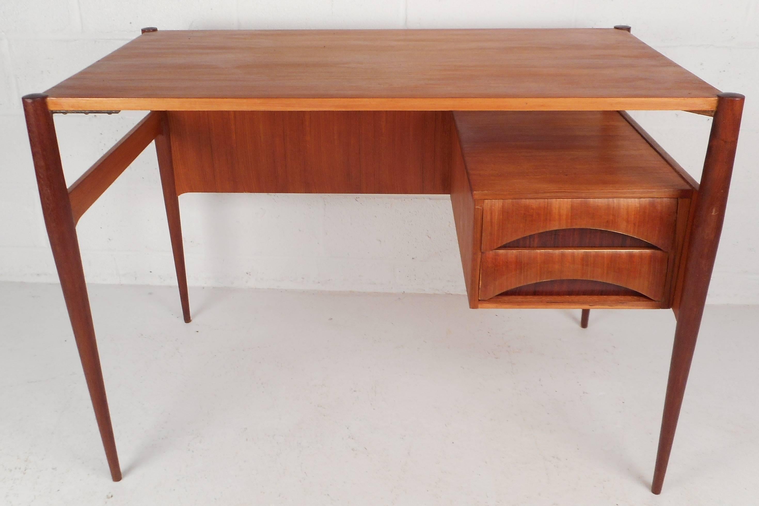 Stunning Mid-Century Modern Italian writing desk has two hefty drawers with eclipse pulls. The sleek two-tone design features teak and rosewood. Stylish tapered legs and a finished back make it the perfect addition to any modern interior. Newly