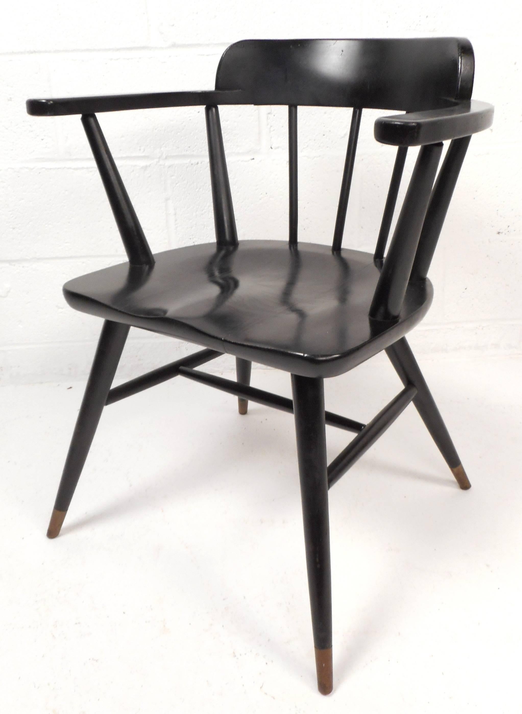Gorgeous set of four vintage modern dining chairs in the style of designer Paul McCobb. Sleek design features a spindle back with an ebony finish. The unique tapered legs have brass capped feet and the seat is sculpted for optimal comfort. High arm