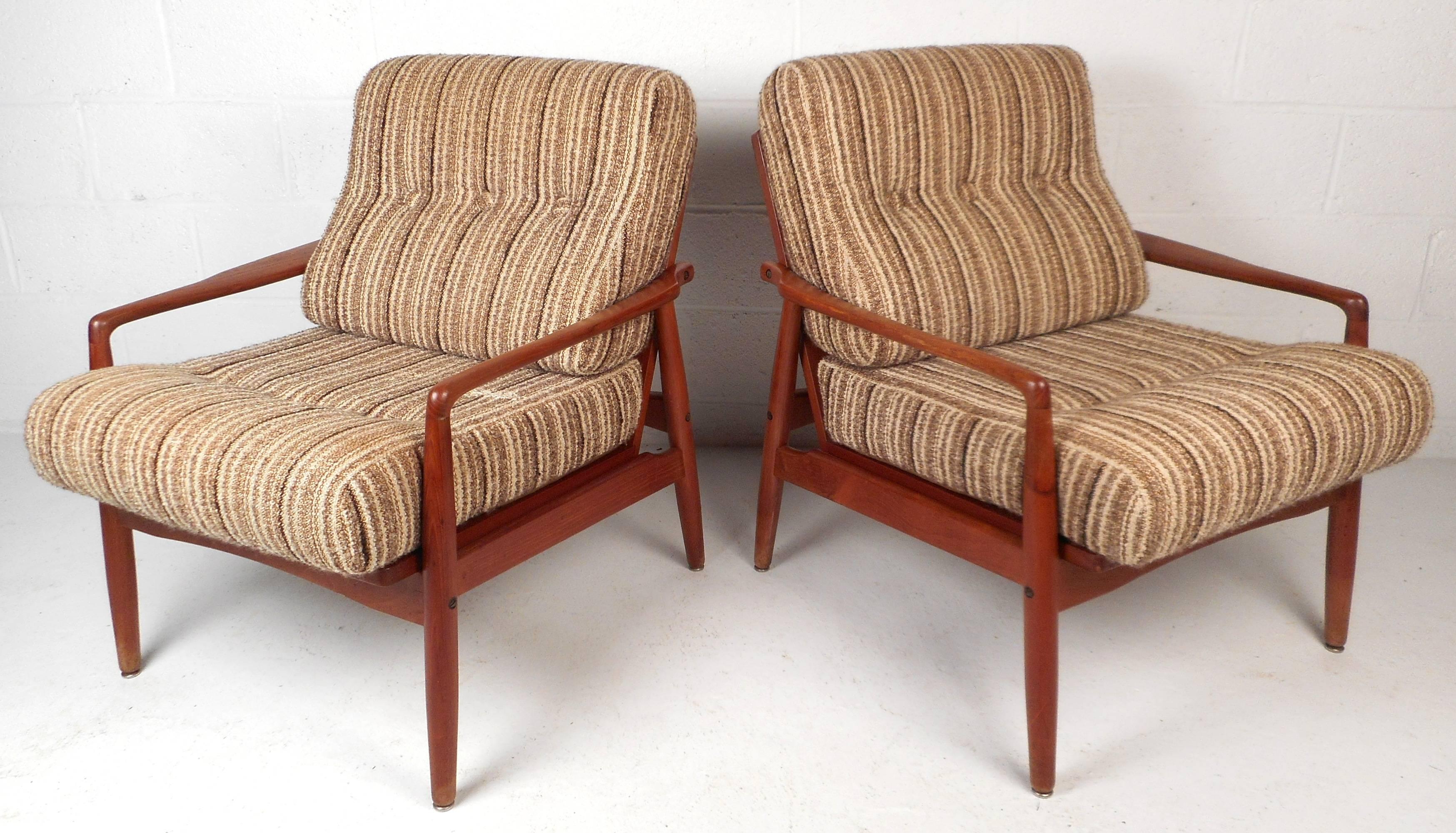 Gorgeous Mid-Century Modern pair of Danish lounge chairs with a vintage teak finish. Stylish and sturdy design with unique sculpted armrests. Beautiful upholstery, thick cushions, and wide seating offer comfort in any modern interior. Made in