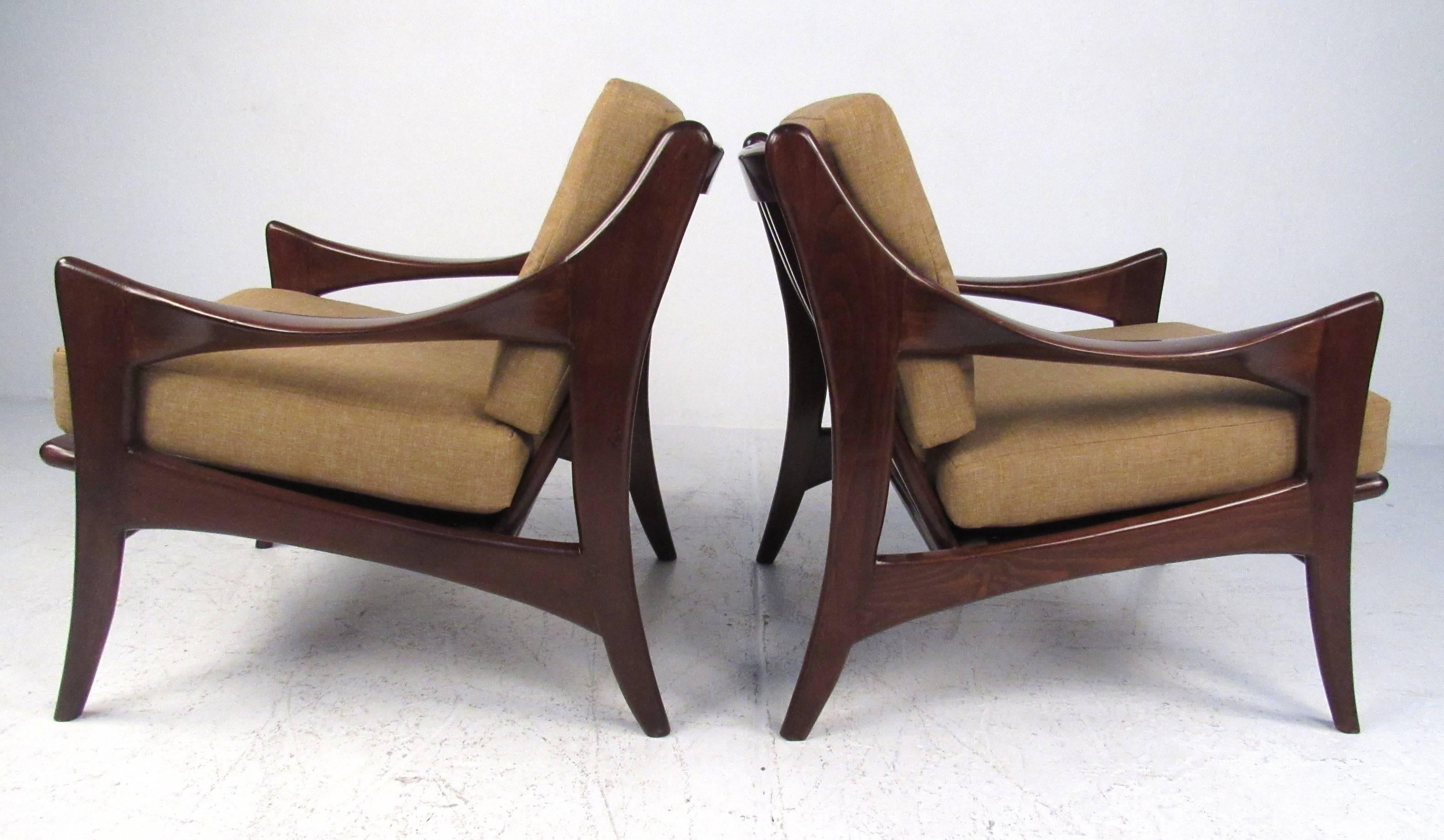 Stylish and comfortable pair teak frame lounge chairs with wide sloped arms and slat backs. The thick padded removable cushions are covered in original yellow fabric. Please confirm item location (NY or NJ) with dealer.