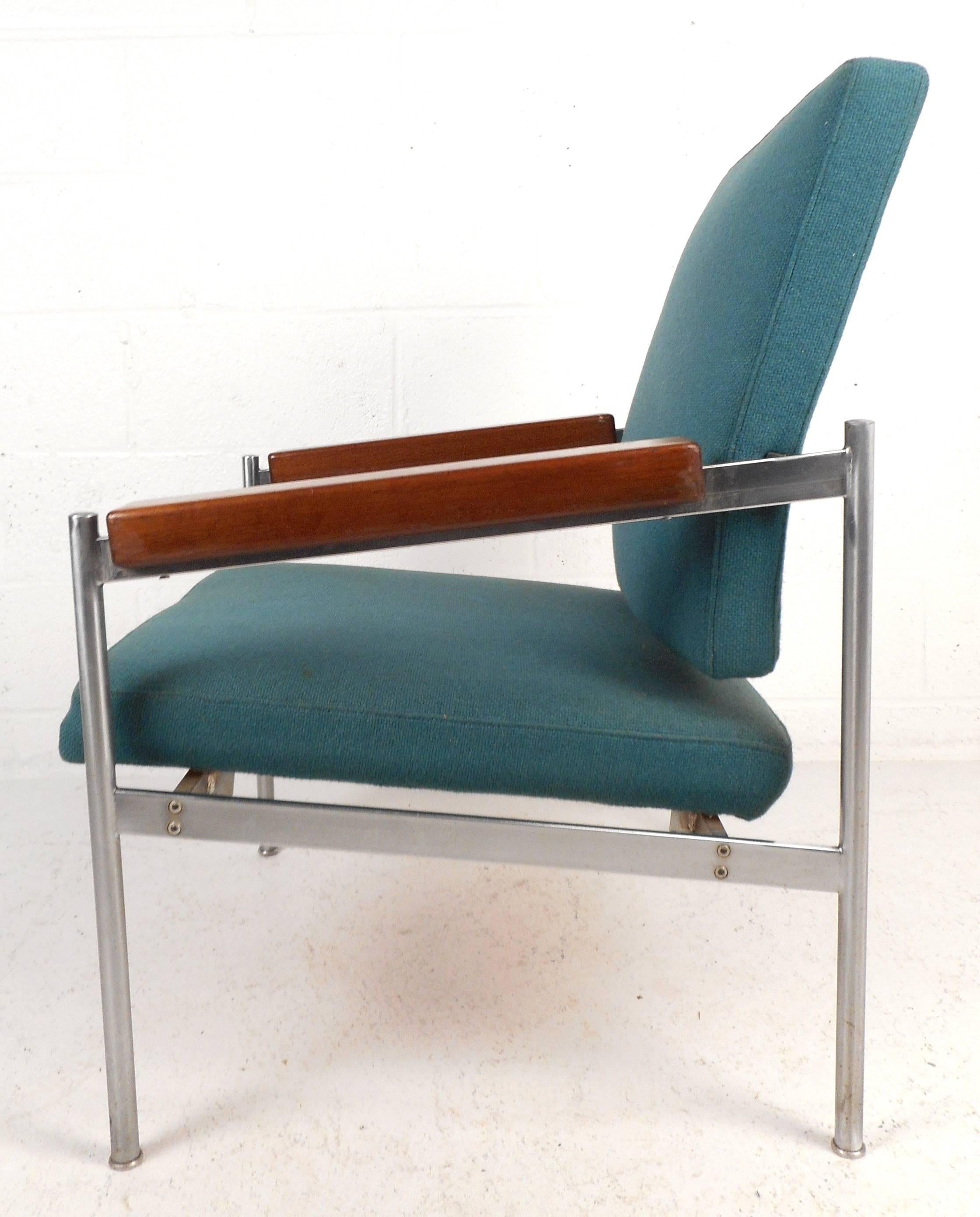 Atemberaubender moderner Loungesessel im Vintage-Stil mit stilvollen schrägen Holzarmlehnen und aquablauer Polsterung. Die ungewöhnliche Kombination von Chrom, Stoff und Holz macht den Reiz aus. Dieser dänische Sessel verleiht jeder Sitzgruppe Stil