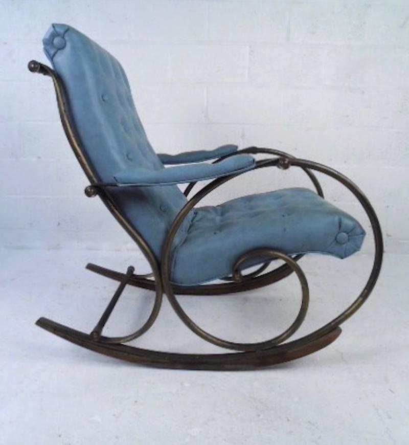 This sculpted metal frame rocking chair with tufted vinyl upholstery makes a stylish and comfortable addition to any seating area. The scrolled metal rockers are balanced with wooden rails, and the upholstered armrests add to the style and comfort