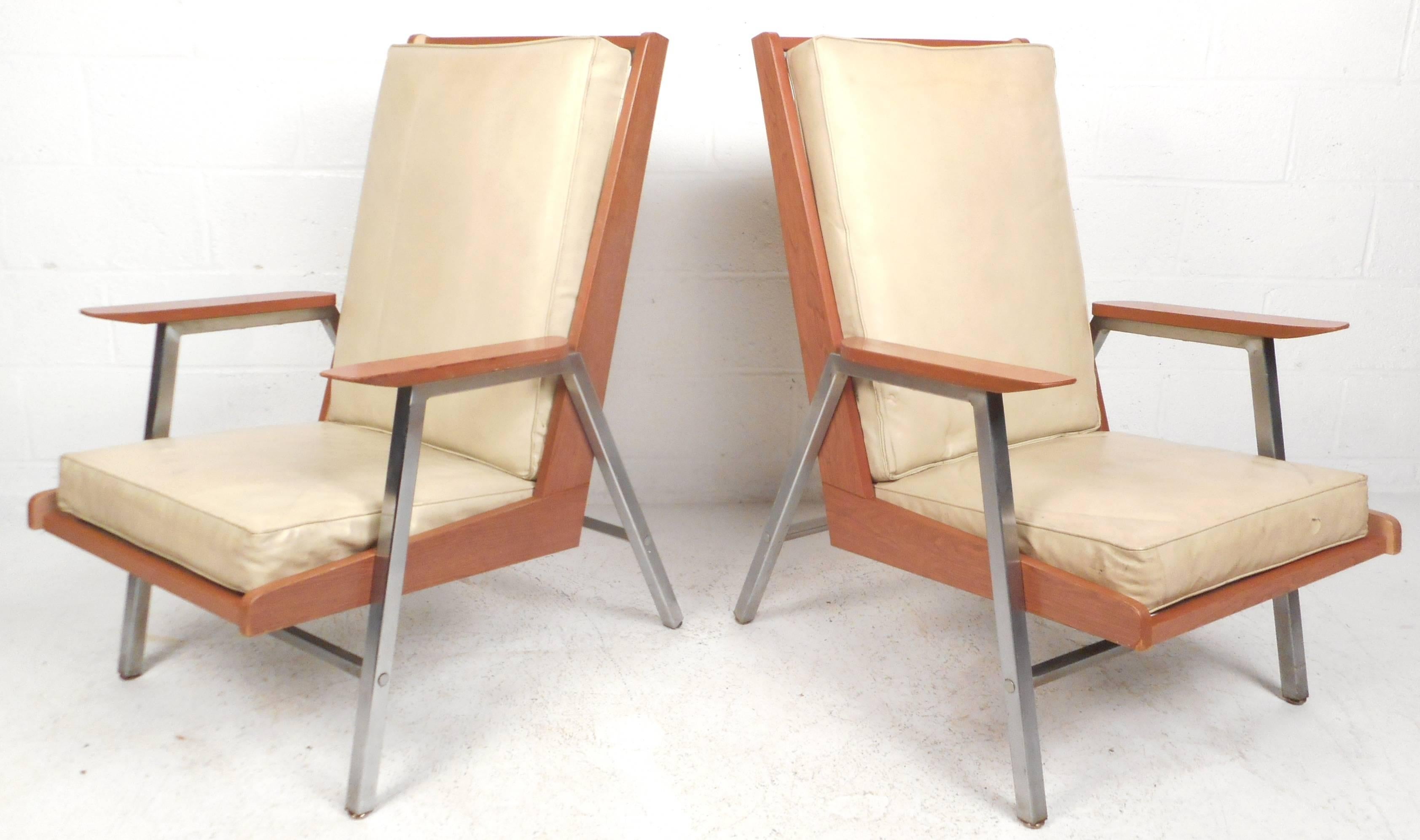 Elegant pair of vintage modern lounge chairs feature a two-tone frame with heavy chrome and wood laminate. Unique design offers plenty of comfort with its high backrest, wide seating, and thick padded vinyl cushions. These sturdy and stylish