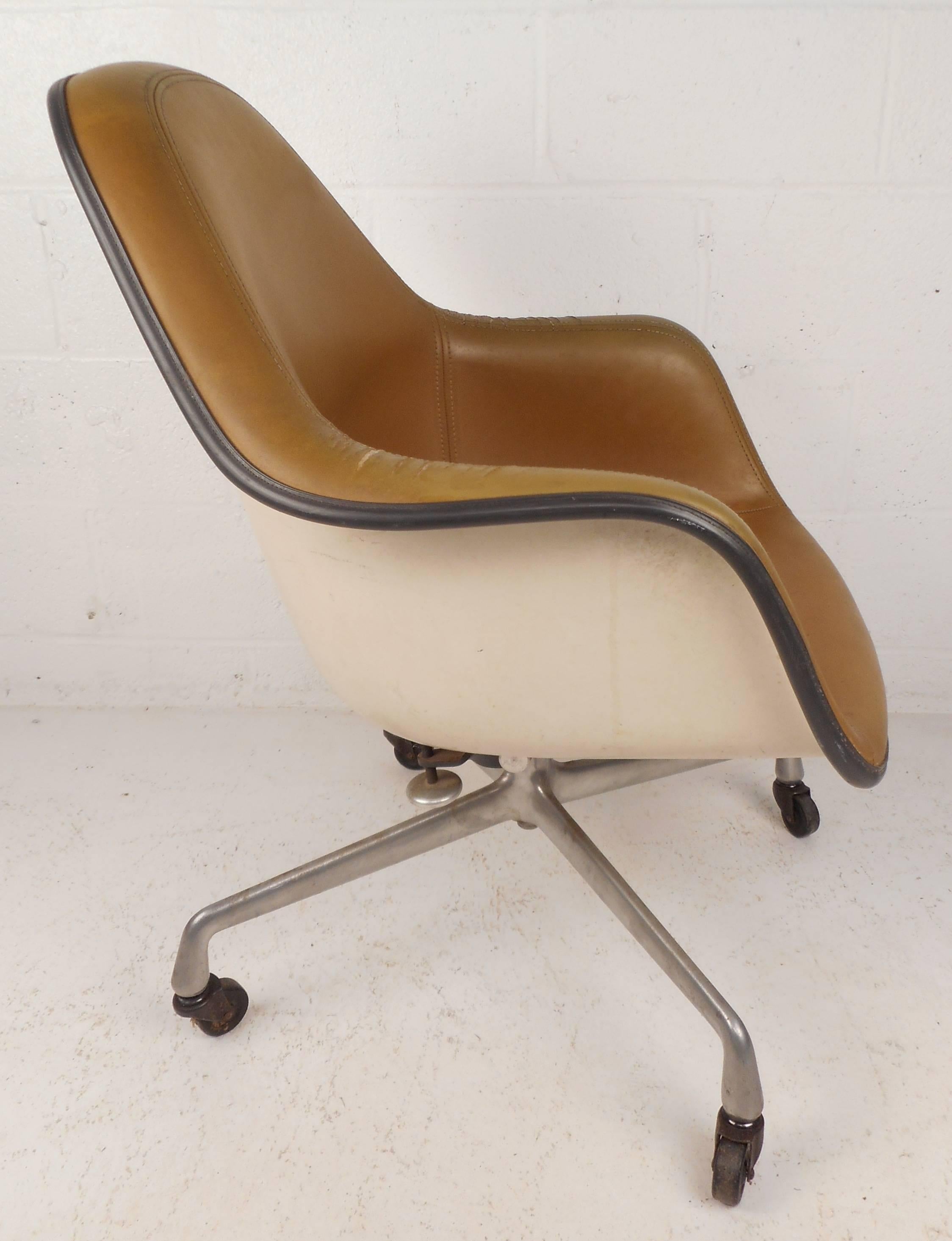 Beautiful vintage modern desk chair by Herman Miller features iconic strand fiberglass shell design with stitched vinyl upholstery. Stylish office chair has a chrome base with wheels ensuring comfort and convenience. Original stamp on bottom reads,