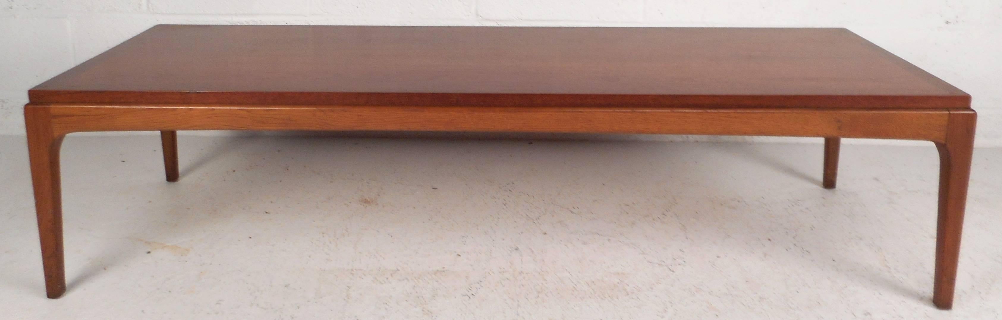 Gorgeous vintage modern coffee table with unique raised top and four sturdy legs. The makers mark and serial number on the bottom ensuring quality craftsmanship. Elegant walnut wood grain and clean lines add style and grace to any modern interior.