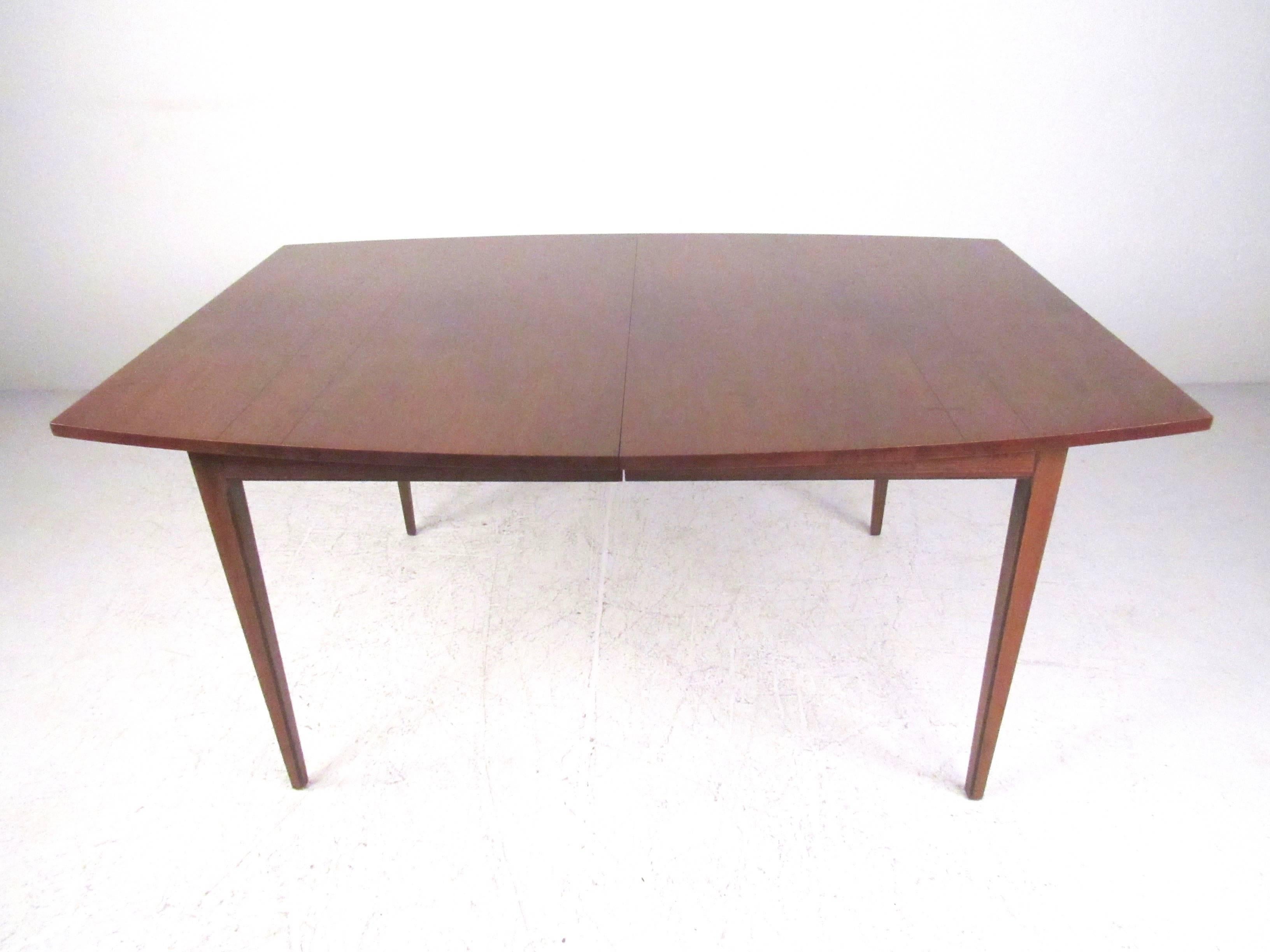 This beautiful American walnut dining set includes a large dining table with six matching chairs. Uniquely shaped seat backs, vintage fabric, and bowtie inlays add to the Mid-Century Modern appeal of this Altavista Lane dining room set. Please