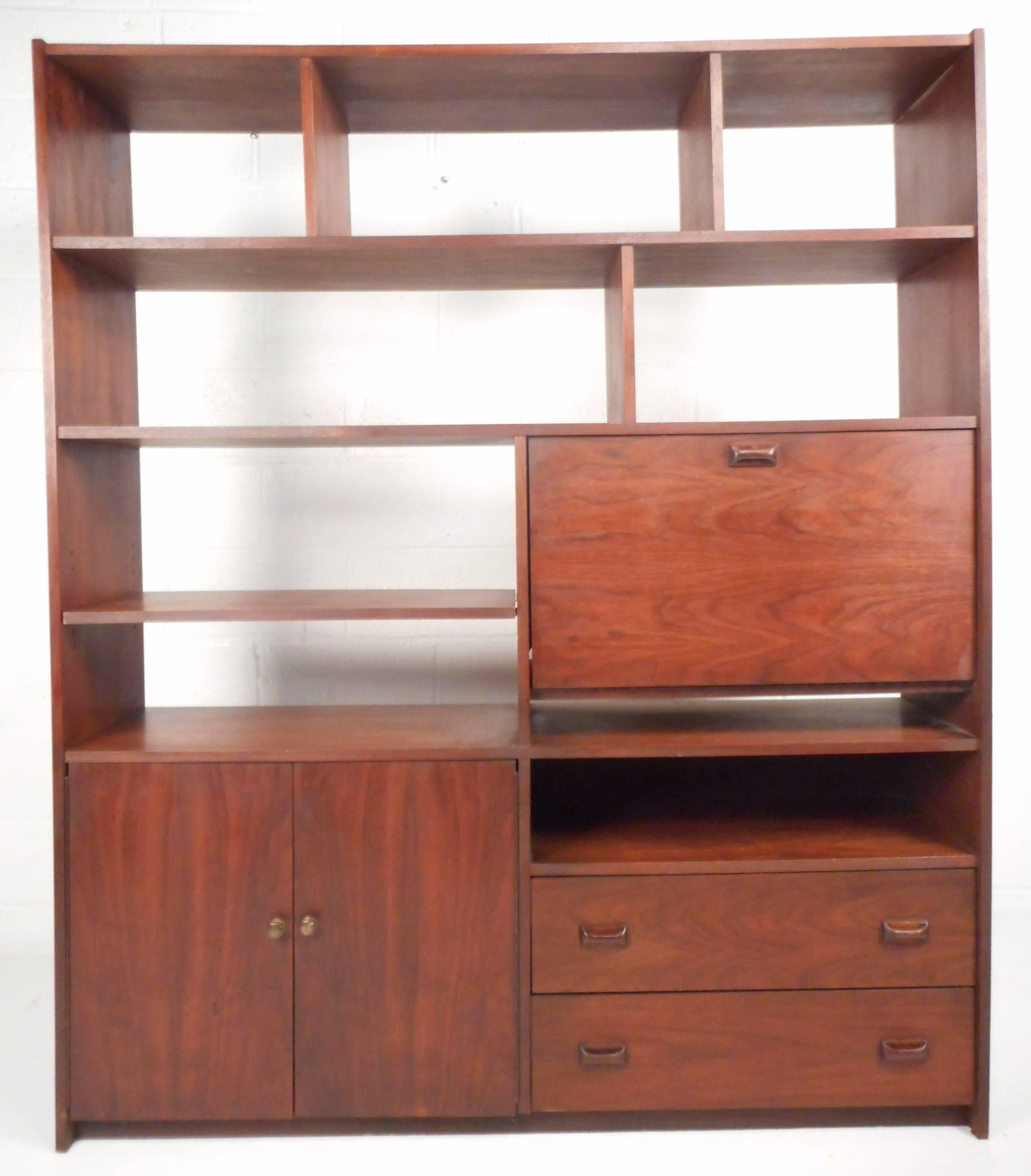 This impressive vintage modern book shelf features nine visible shelves, two hefty drawers, a drop down formica top table and two cabinet doors hiding another shelf. Stunning design offers a plenty of room for storage and display. Gorgeous walnut