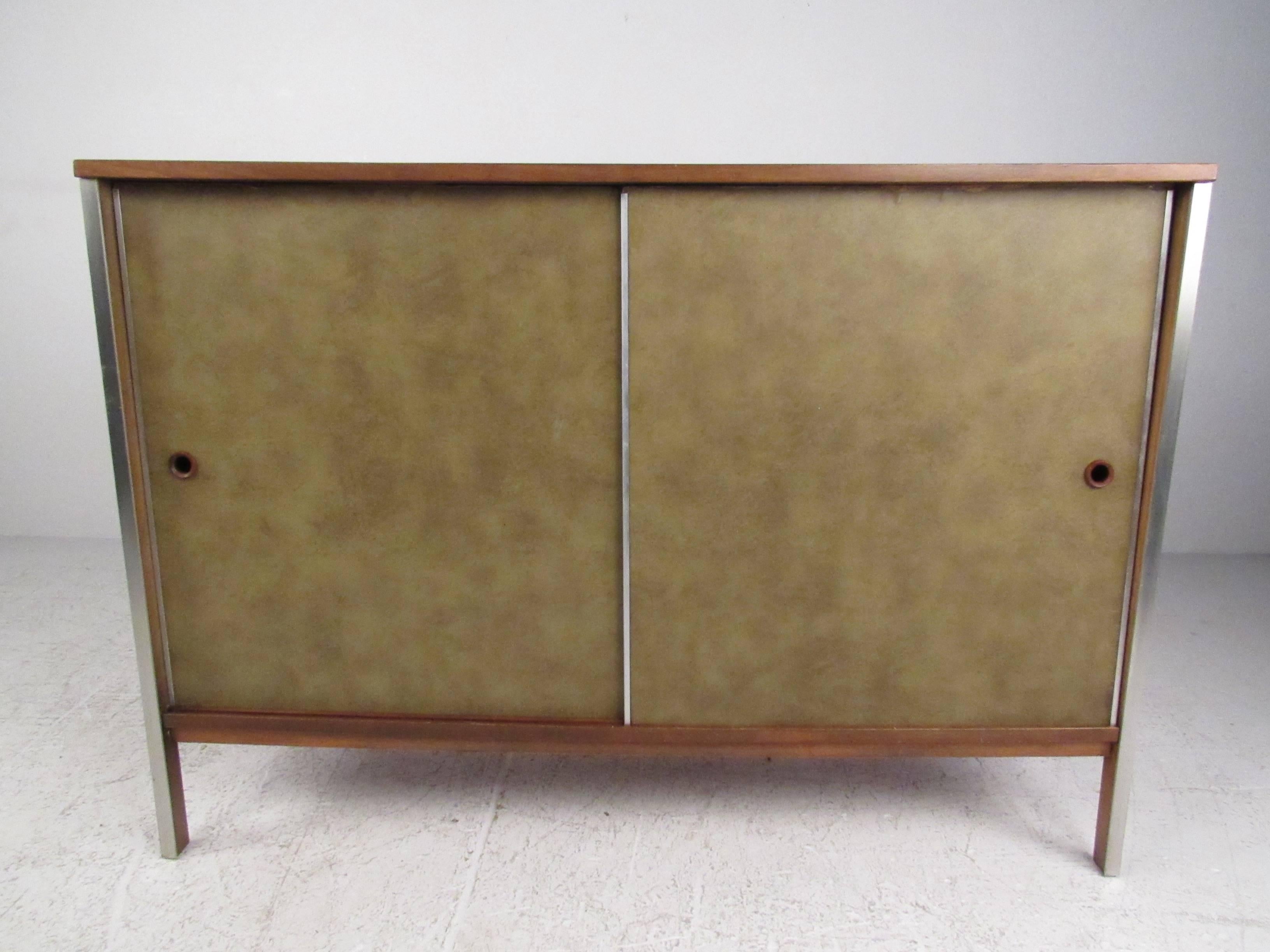 Leatherette covered sliding door cabinet with aluminum trim accents from the Paul McCobb Calvin collection. Please confirm item location (NY or NJ) with dealer.