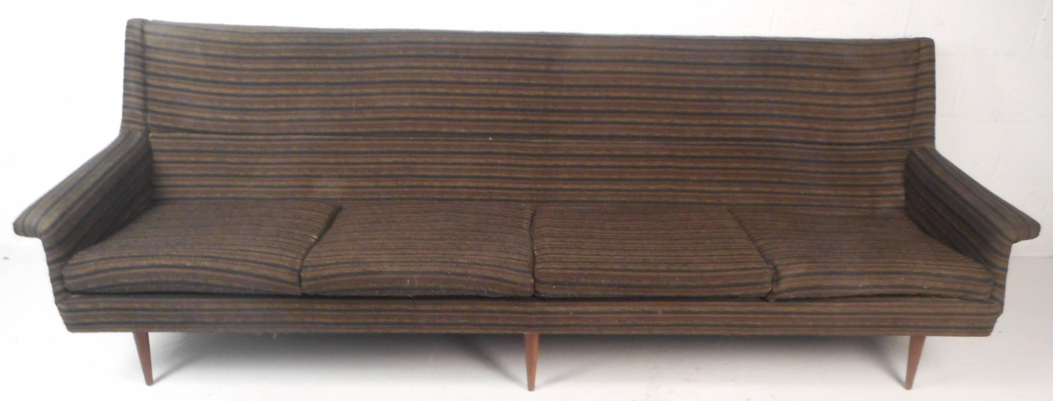 Attractive vintage modern sofa with unique wing shaped arm rests. Sleek design with clean mid-century line work combined with extreme comfort. Impressive sofa displays quality construction with six tapered and angled walnut legs ensuring sturdiness.