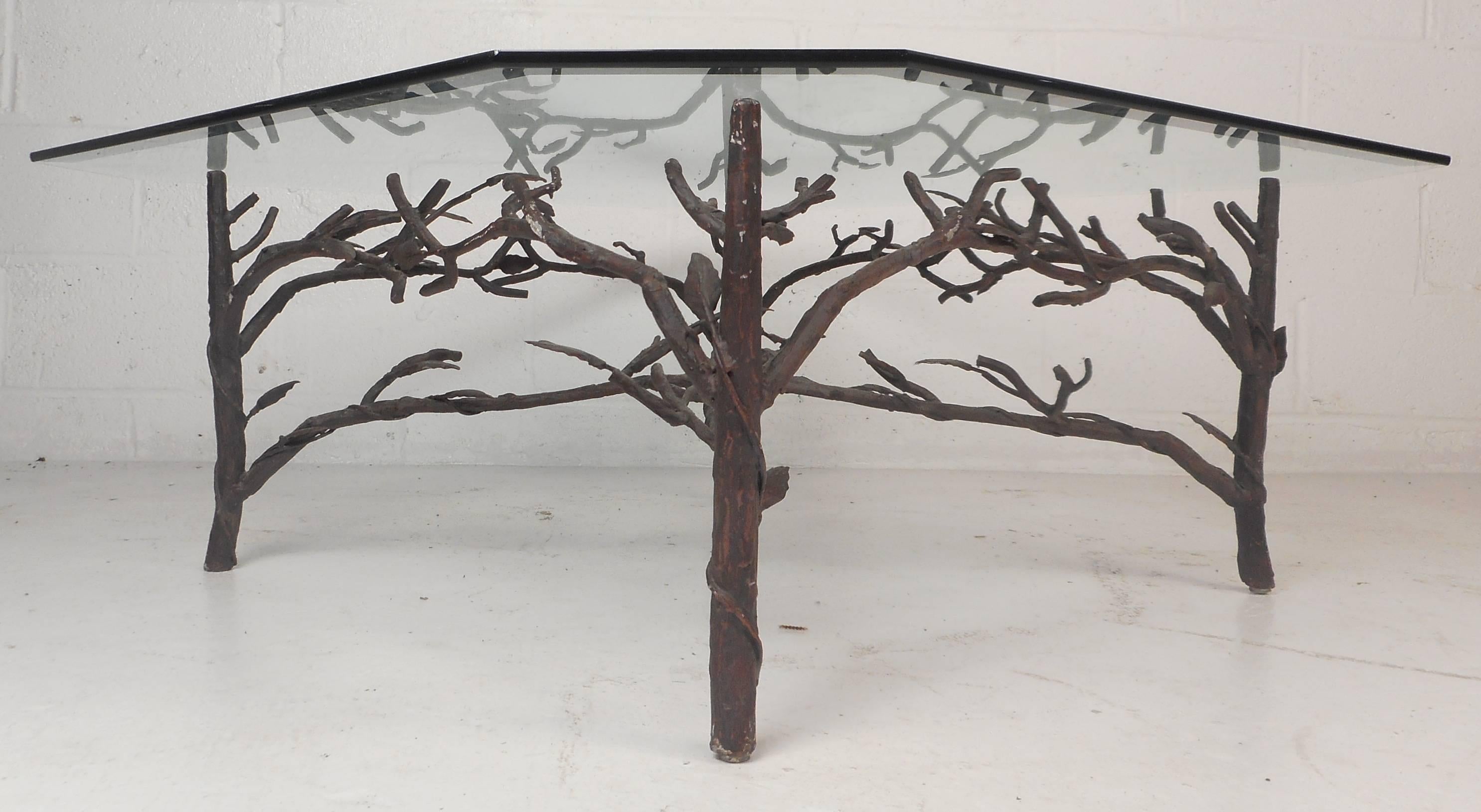 Stunning contemporary modern coffee table features a metal base with a unique tree limb design. The sturdy metal base displays vintage patina and intricate detail. Impressive thick glass with beveled edges and a light green tint sits comfortably on
