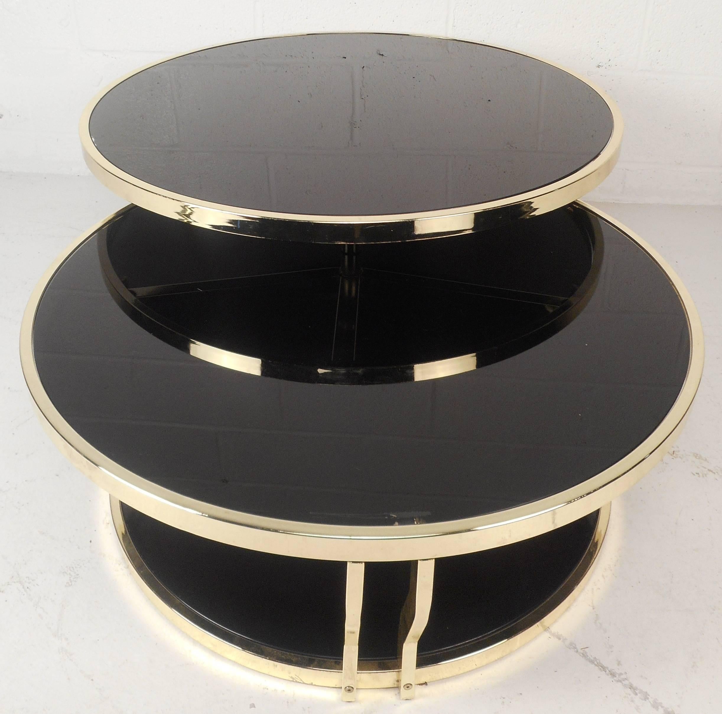 This beautiful vintage modern Italian coffee table offers the ability to swivel the top tier for extra space and convenience. Versatile three tier design with a brass frame and dark smoked glass table tops. The sculpted sides ensure sturdiness and