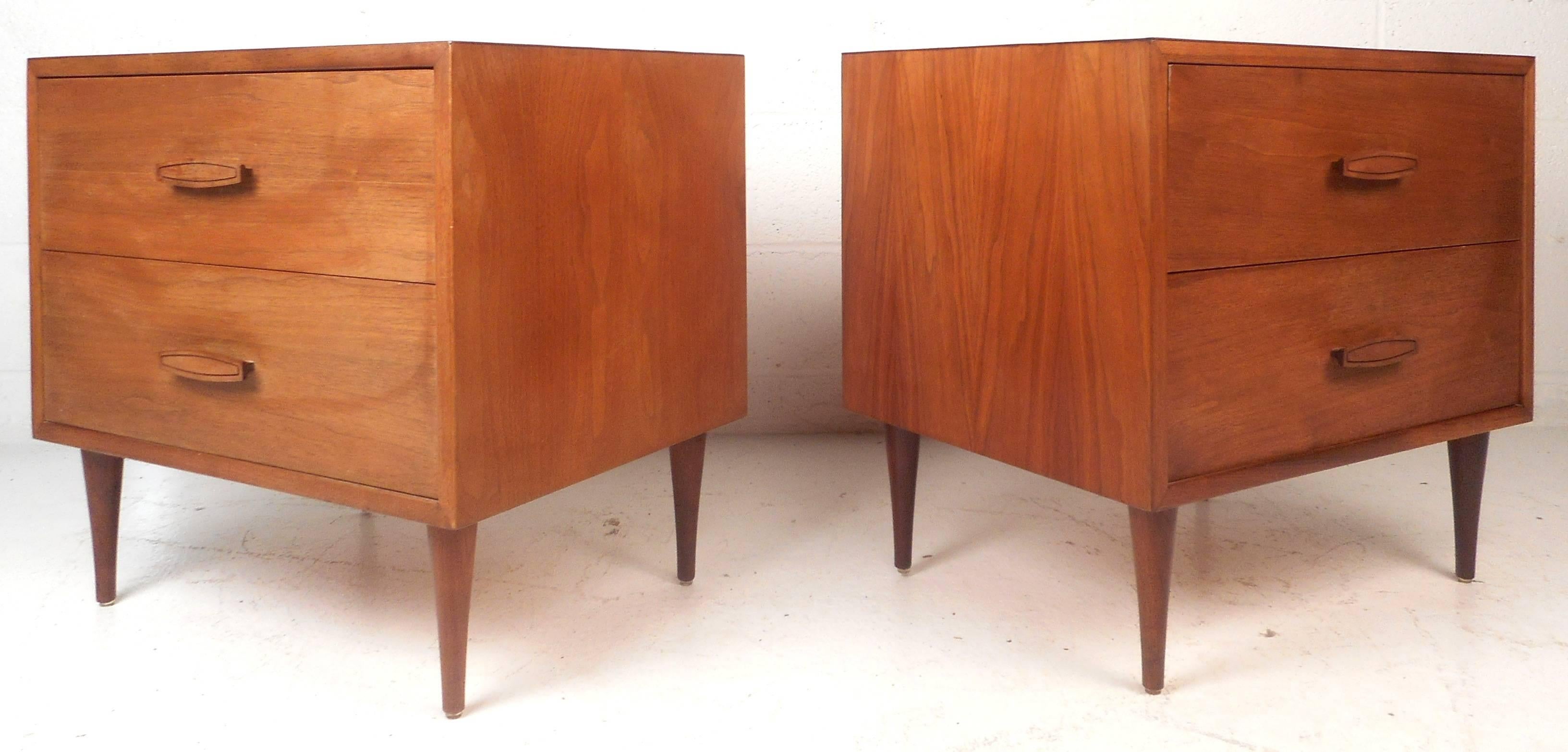 Handsome pair of vintage modern nightstands feature sculpted pulls and tapered legs. Sleek design with two large drawers and beautiful walnut wood grain. This impressive pair offers plenty of storage space without sacrificing style in any modern