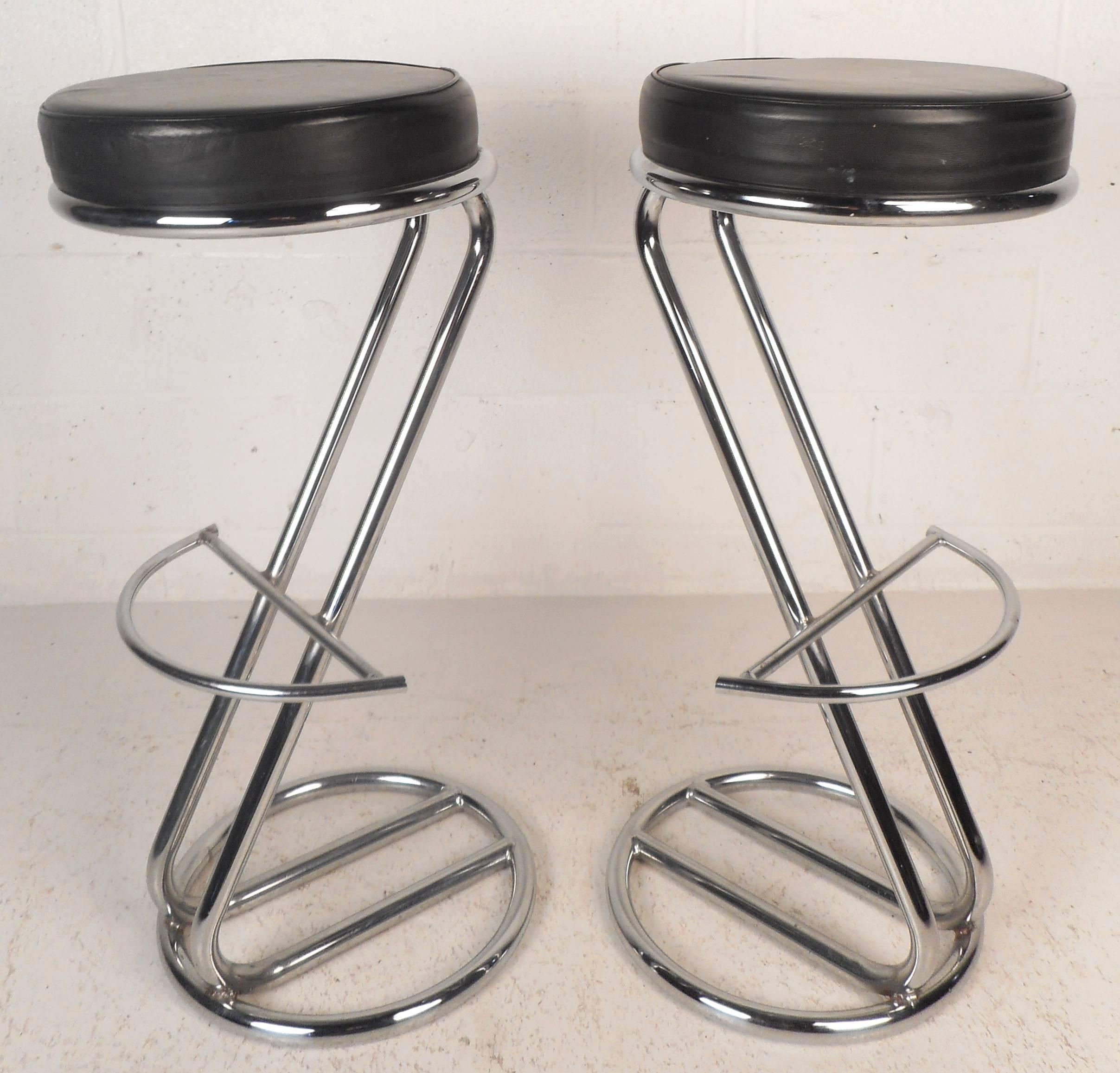 This beautiful pair of vintage modern cantilever bar stools feature tubular chrome bases. Elegant floating top design with round black leather seats and a unique eclipse kick rest. This stunning Mid-Century pair of stools are sure to compliment any