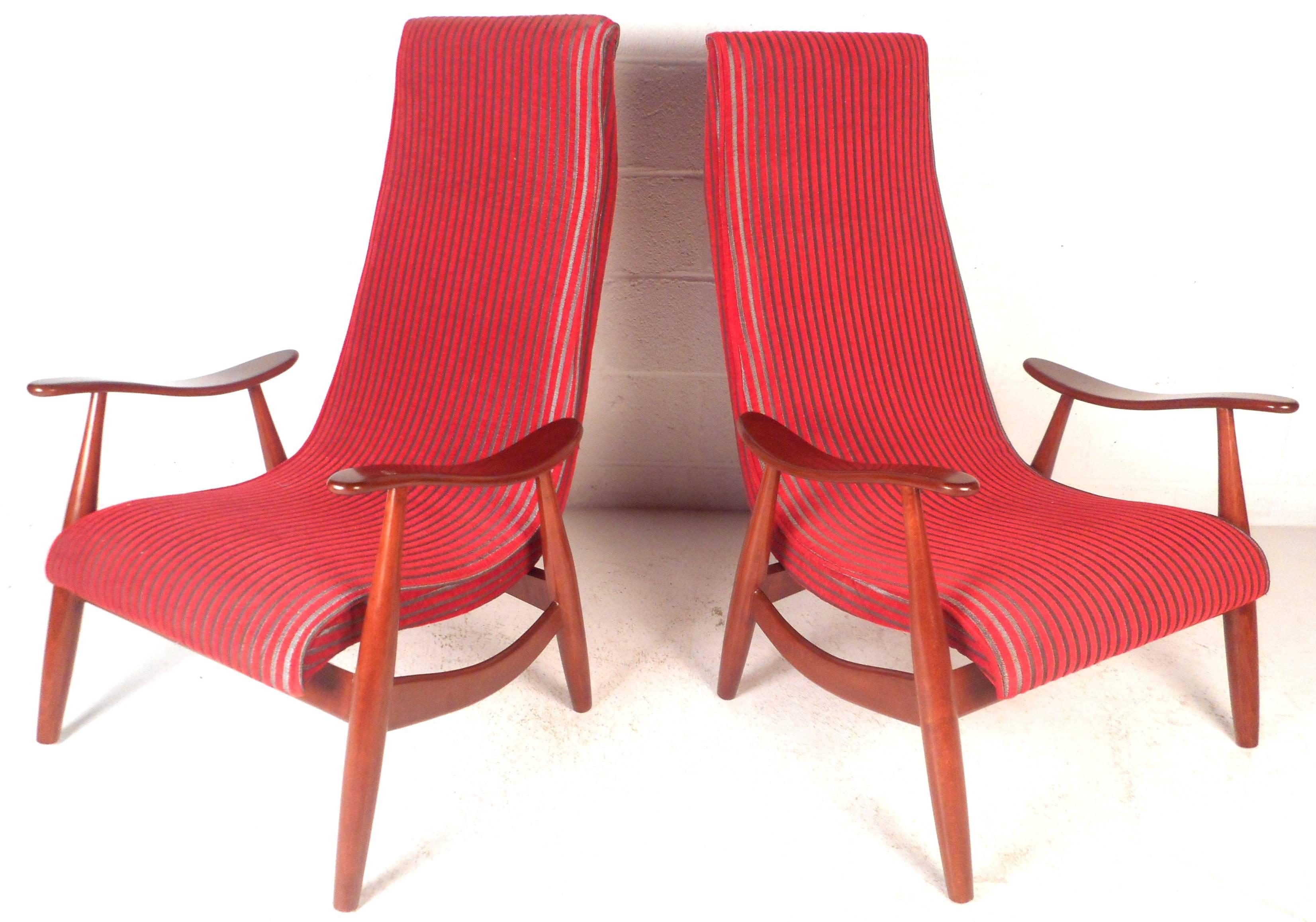 This beautiful pair of vintage modern lounge chairs feature a solid walnut frame with sculpted arm rests. Sleek design with unique angled legs, stylish curved stretchers, and a high backrest. Comfortable seating wonderfully upholstered in plush red