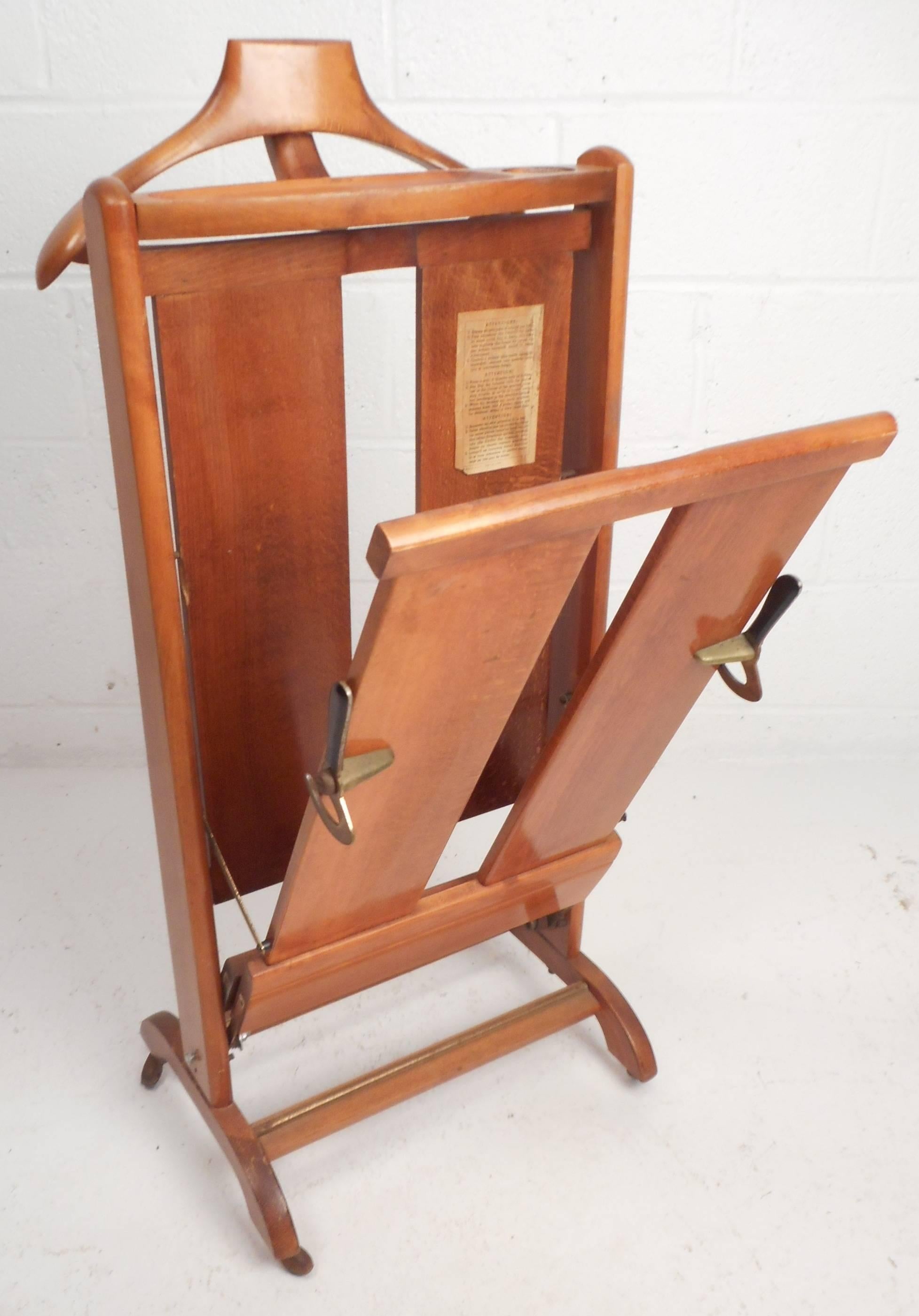 This gorgeous vintage suit stand features brass detail and sculpted feet. The sleek design has various options for hanging and pressing clothes. The original directions are on in the inside and includes a tray on the top, unique brass latches, and a