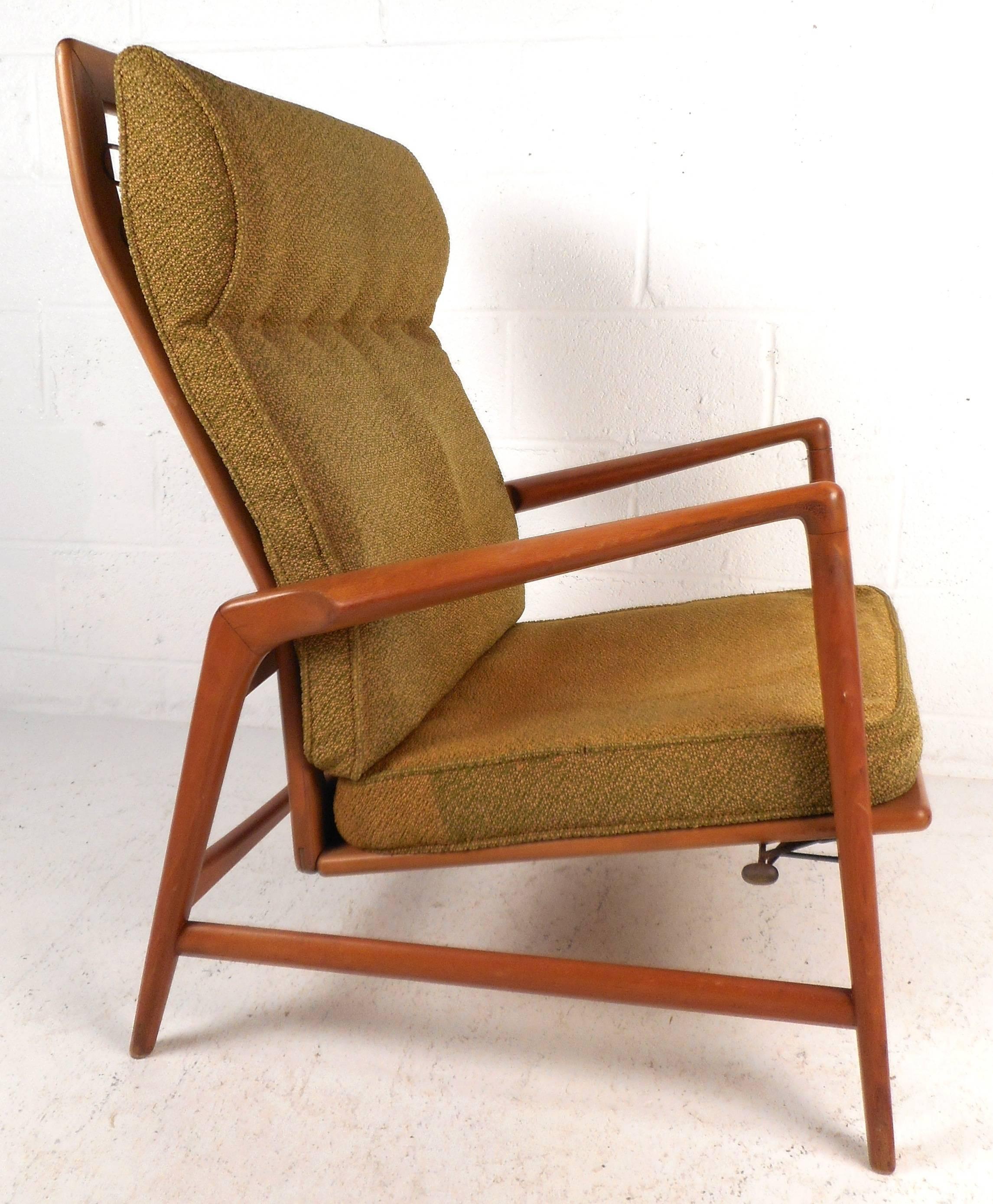 This attractive vintage modern lounge chair features a solid teak frame with smooth angled arm rests. The sleek design has the ability to recline comfortably while maintaining a stylish appearance. Wonderful sculptural details and a high backrest