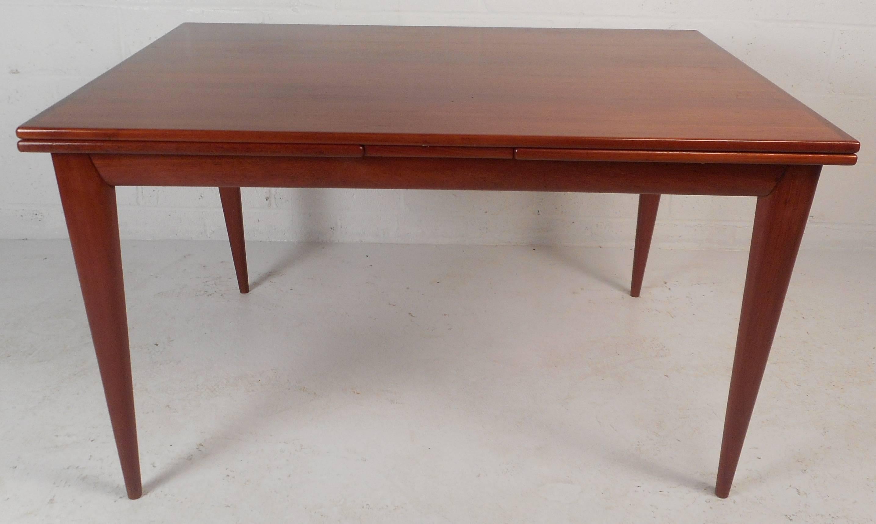 This elegant vintage modern dining table features two hidden leaves that extend the width all the way to 93.25 inches. Versatile design with unique angled legs and beautiful teak wood grain. This Mid-Century piece offers plenty of room for guests