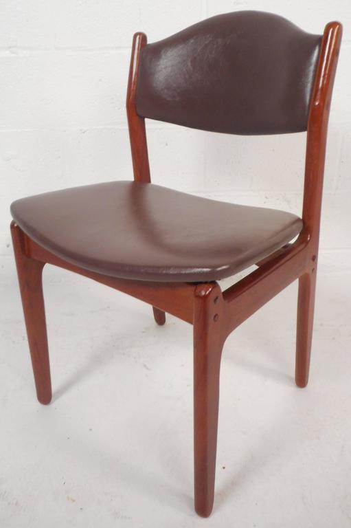 This beautiful set of six vintage modern dining chairs feature floating seats and comfortable angled back rests. The elegant teak wood grain and vinyl upholstery add to the allure. This stylish set includes one armchair and five dining chairs making