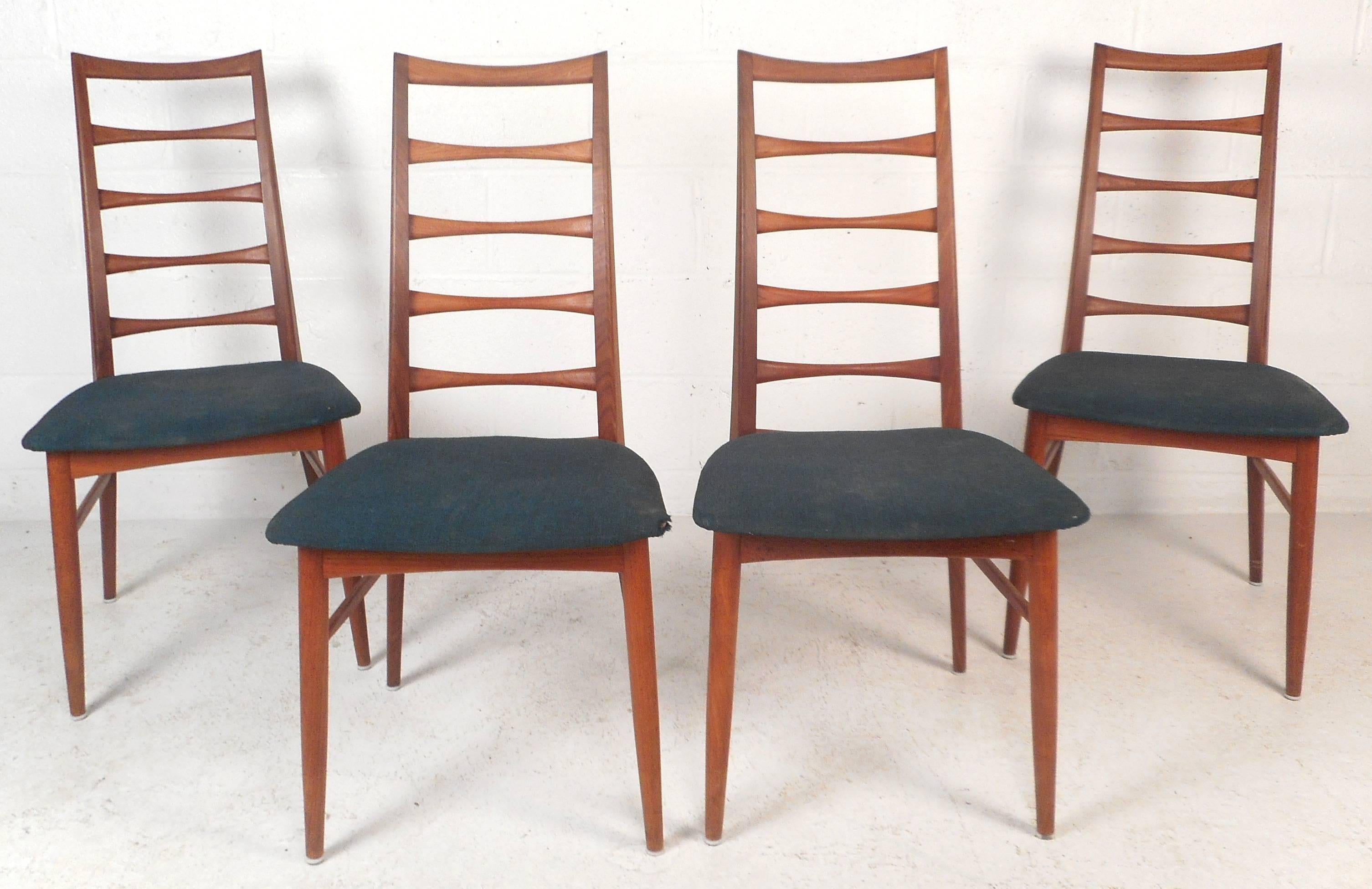 Stunning set of four vintage modern dining chairs feature unique ladder back rests and upholstered seats. Sleek design ensures comfort with angled back legs and a tall backrest. This unique set displays quality craftsmanship with beautiful teak wood