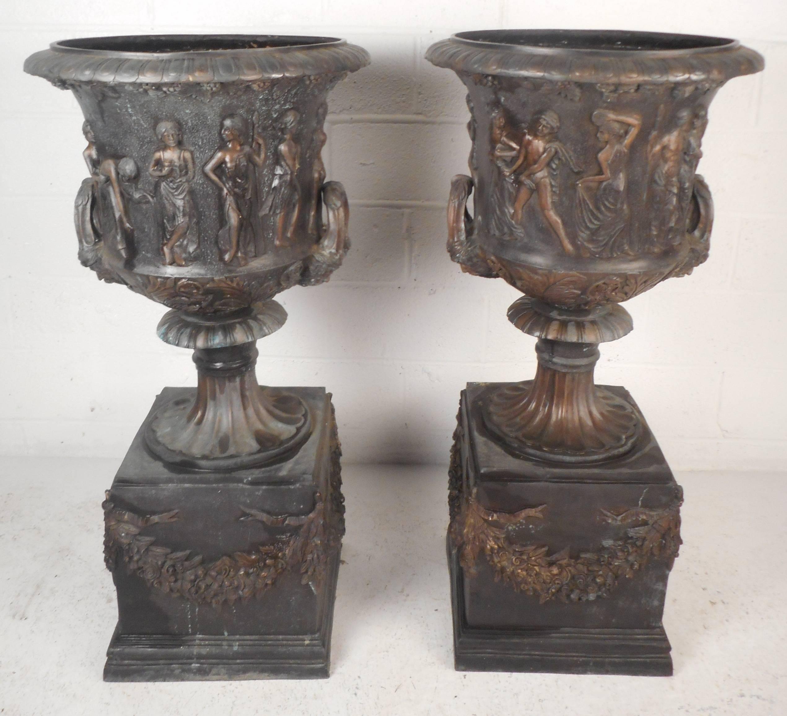 Stunning pair of Medici style bronze urns feature a wide classical figural Bacchnalian frieze over a wide petal form band. Intricate detail on beautifully patinated bronze. This impressive pair of pedestal urns look elegant with flowers or simply as