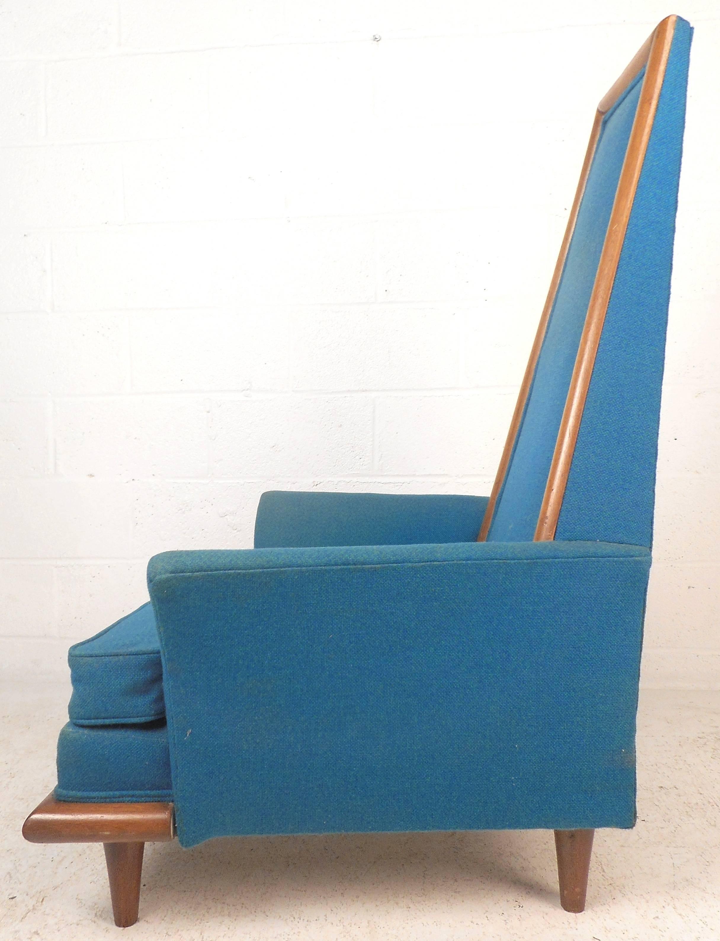 Beautiful vintage modern lounge chair features walnut trim around the sculpted backrest and base. Sleek design with unique winged arm rests, walnut legs, and elegant royal blue upholstery. The unusual shape displays quality craftsmanship making this