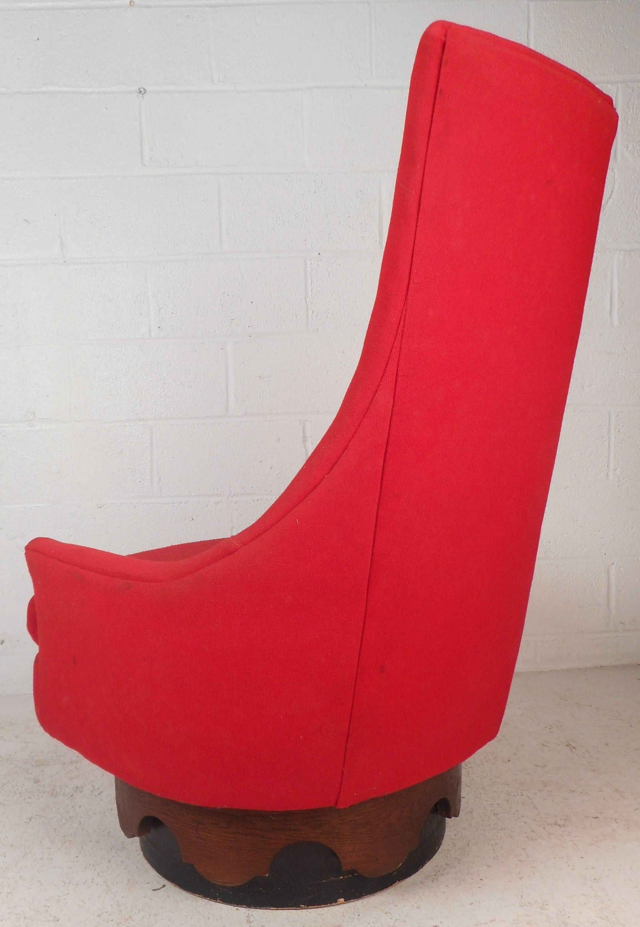 Beautiful vintage modern lounge chair features an unusual high tufted backrest with a sculpted walnut design on the base. Stylish design offers the ability to swivel and is covered in an elegant red upholstery. This wonderful Mid-Century lounge