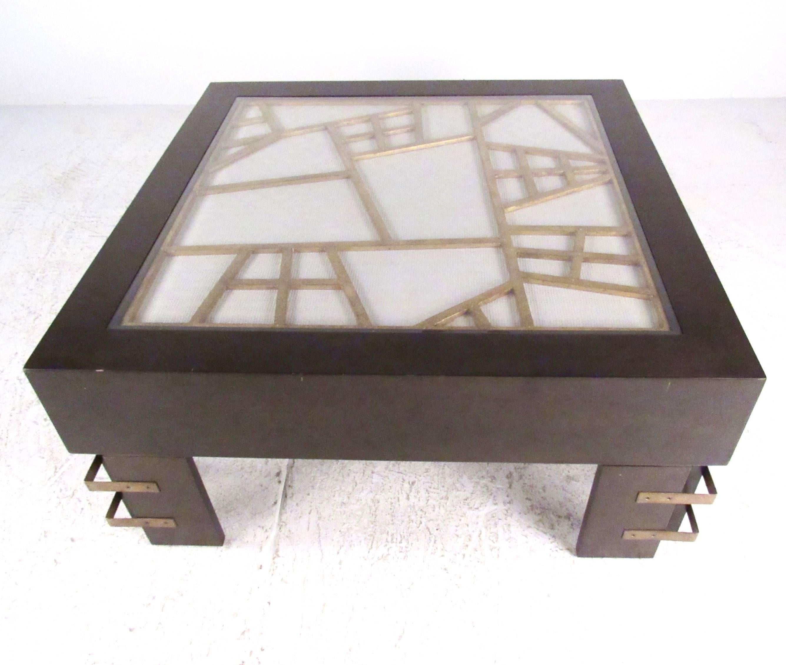 Cette élégante table basse moderne présente une construction robuste avec un plateau incrusté texturé sous un verre protecteur. Le design unique des pieds et les lignes épurées ajoutent à l'attrait impressionnant de cette table de cocktail. Veuillez