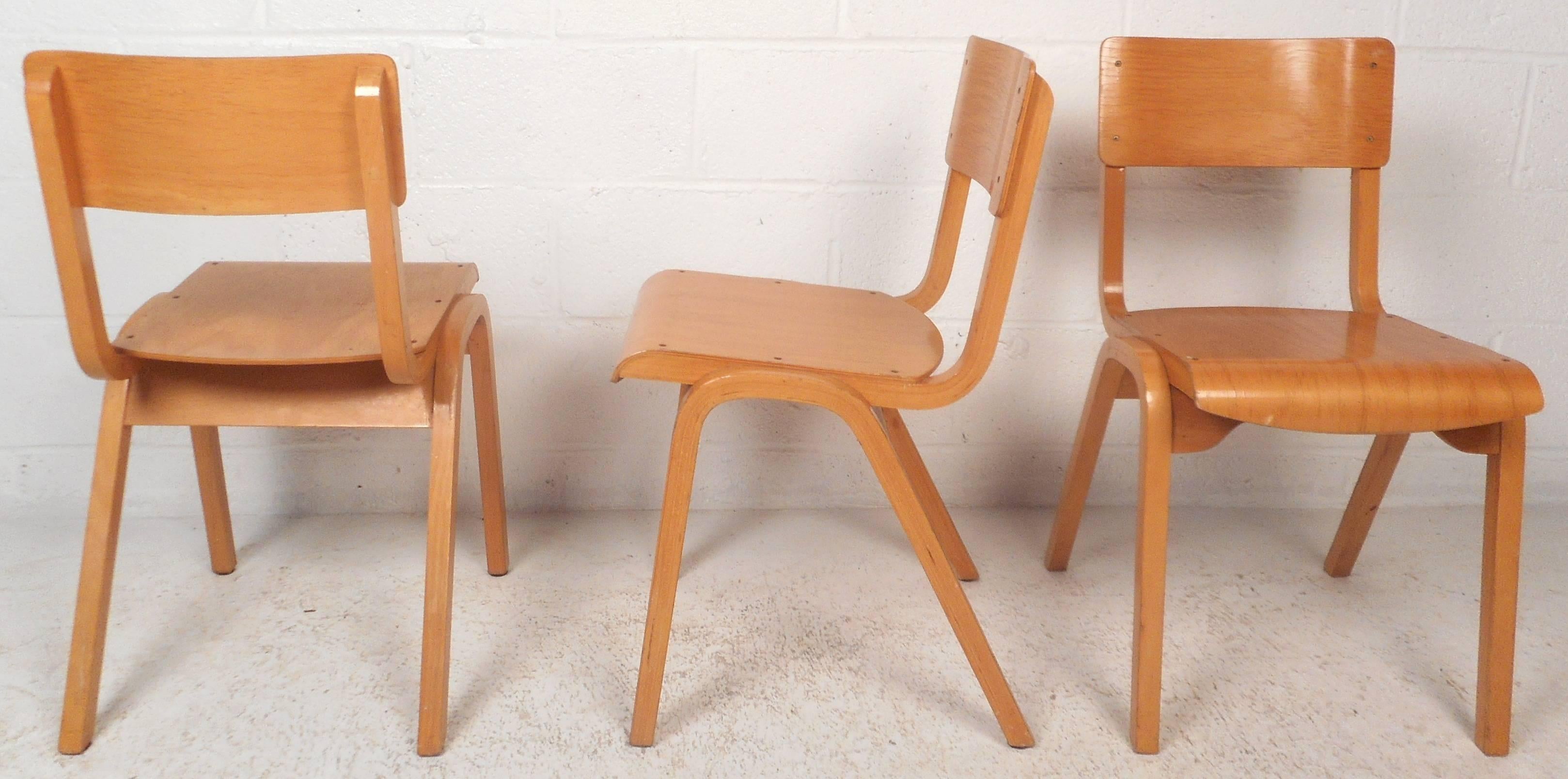 This beautiful set of four vintage modern stacking chairs feature unique angled back legs. The sleek design is made of solid blonde maple wood and offers maximum comfort. Quality craftsmanship with smooth rounded seating and back rests. This elegant