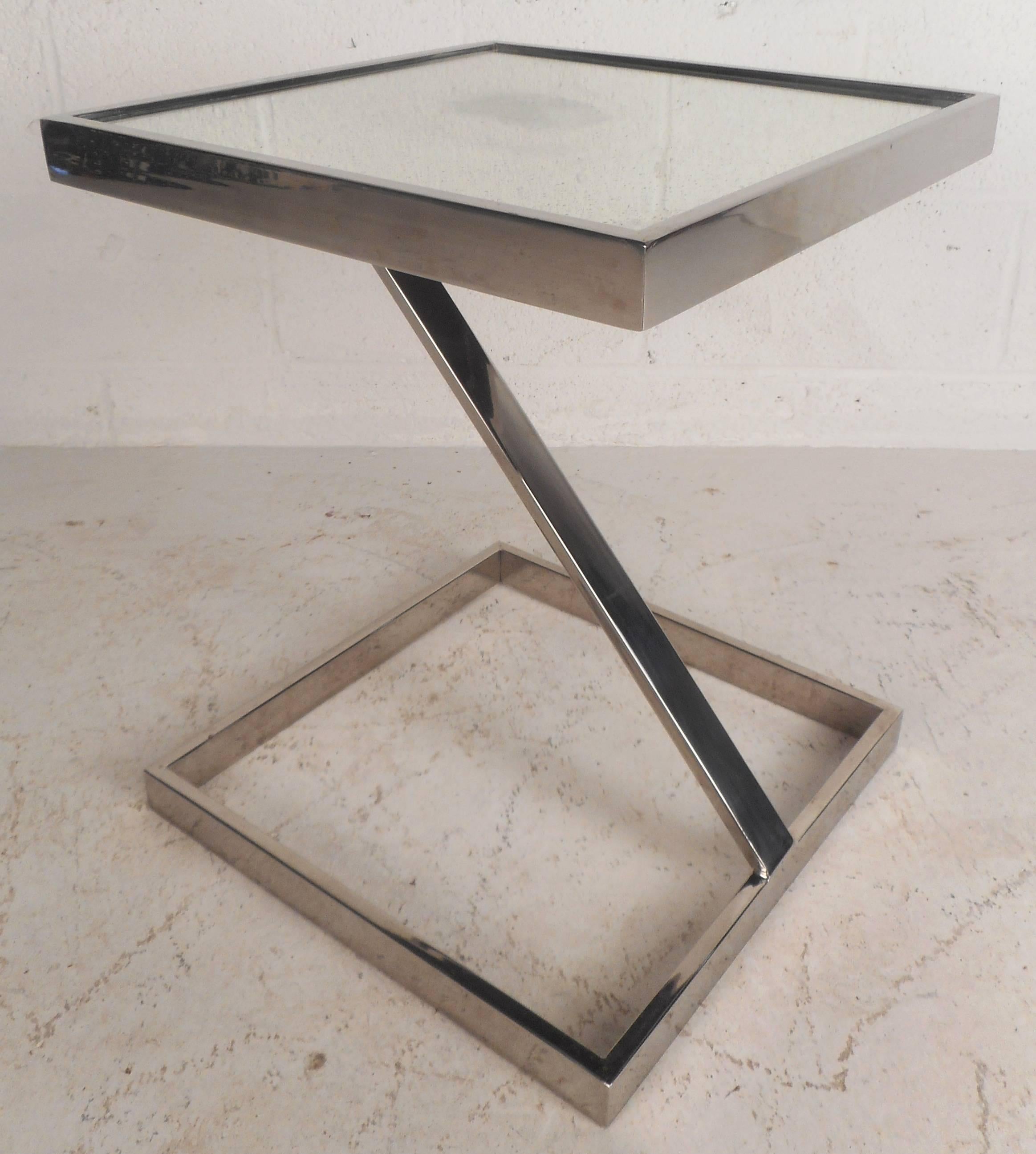 This vintage modern end table features an unusual floating mirrored top with a chrome frame. Sleek design with a unique angled support provides sturdiness without sacrificing style. This elegant Mid-Century piece is sure to compliment any modern