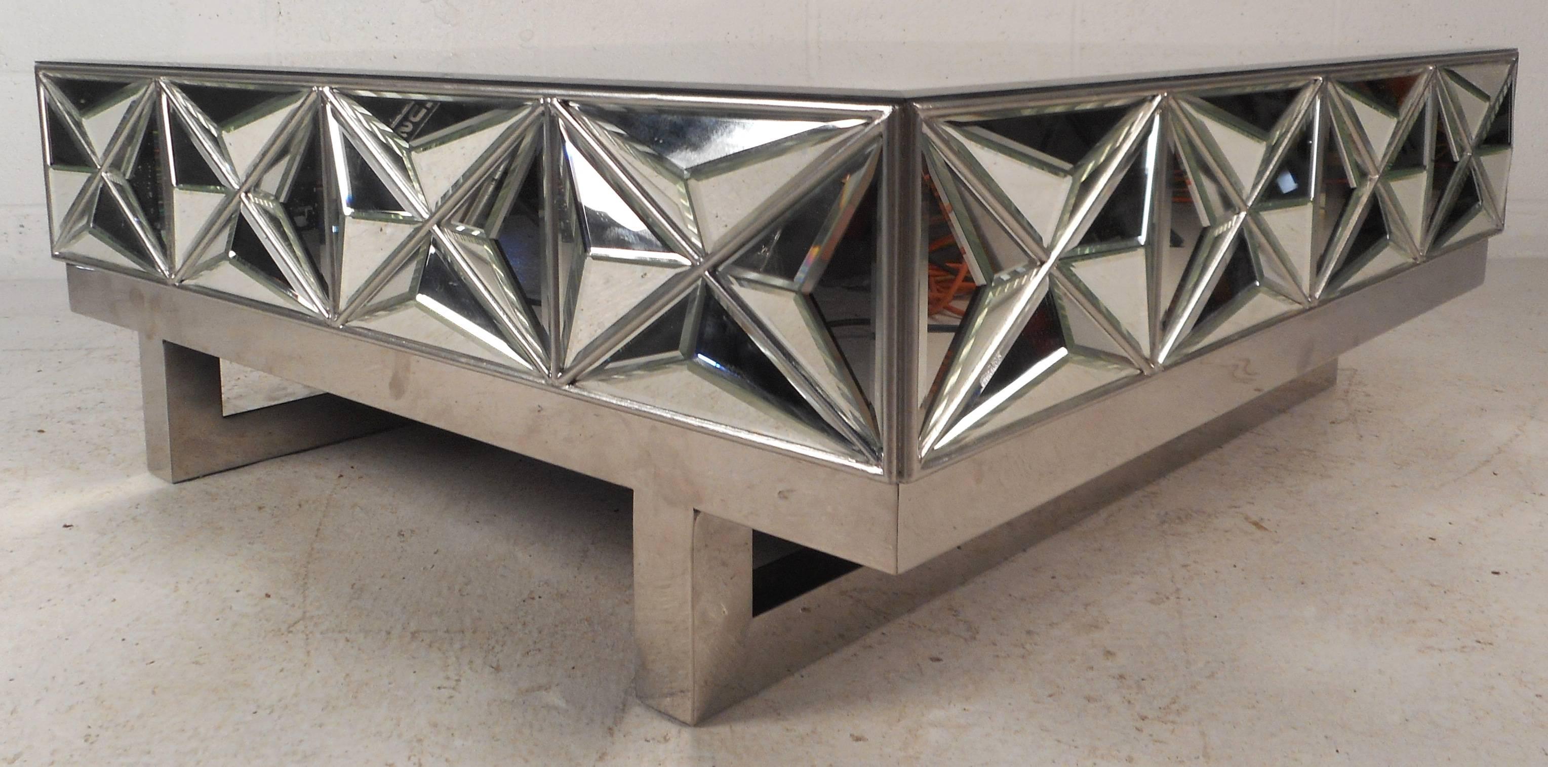 This elegant Mid-Century Modern style coffee table features a beveled mirror top with a stylish sled leg chrome base. Unique beveled diamond designs wraparound all sides of this unusual vintage modern piece. Elaborate and functional design makes the